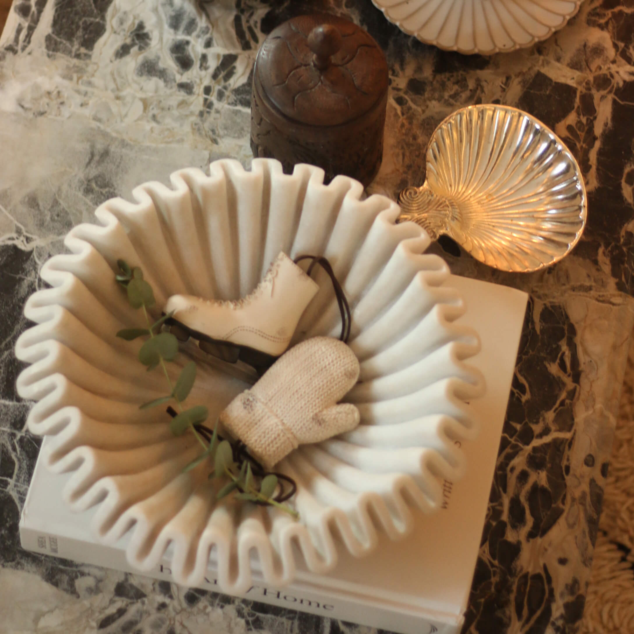 Weiße Keramikschale mit wellenförmigem Rand, dekoriert mit Schlittschuh und Handschuh auf Marmortisch