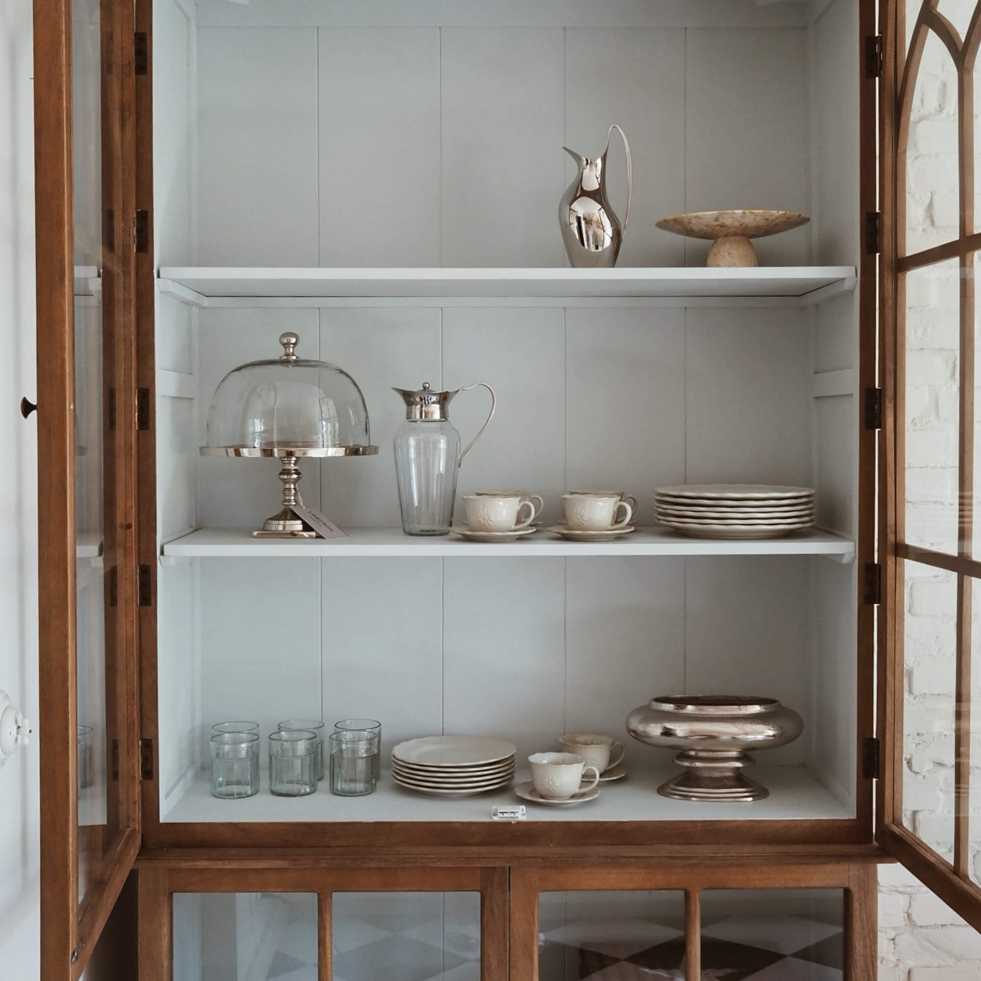 Holzvitrine mit weißen Regalen, Porzellanservice und Gläsern für den Haushalt