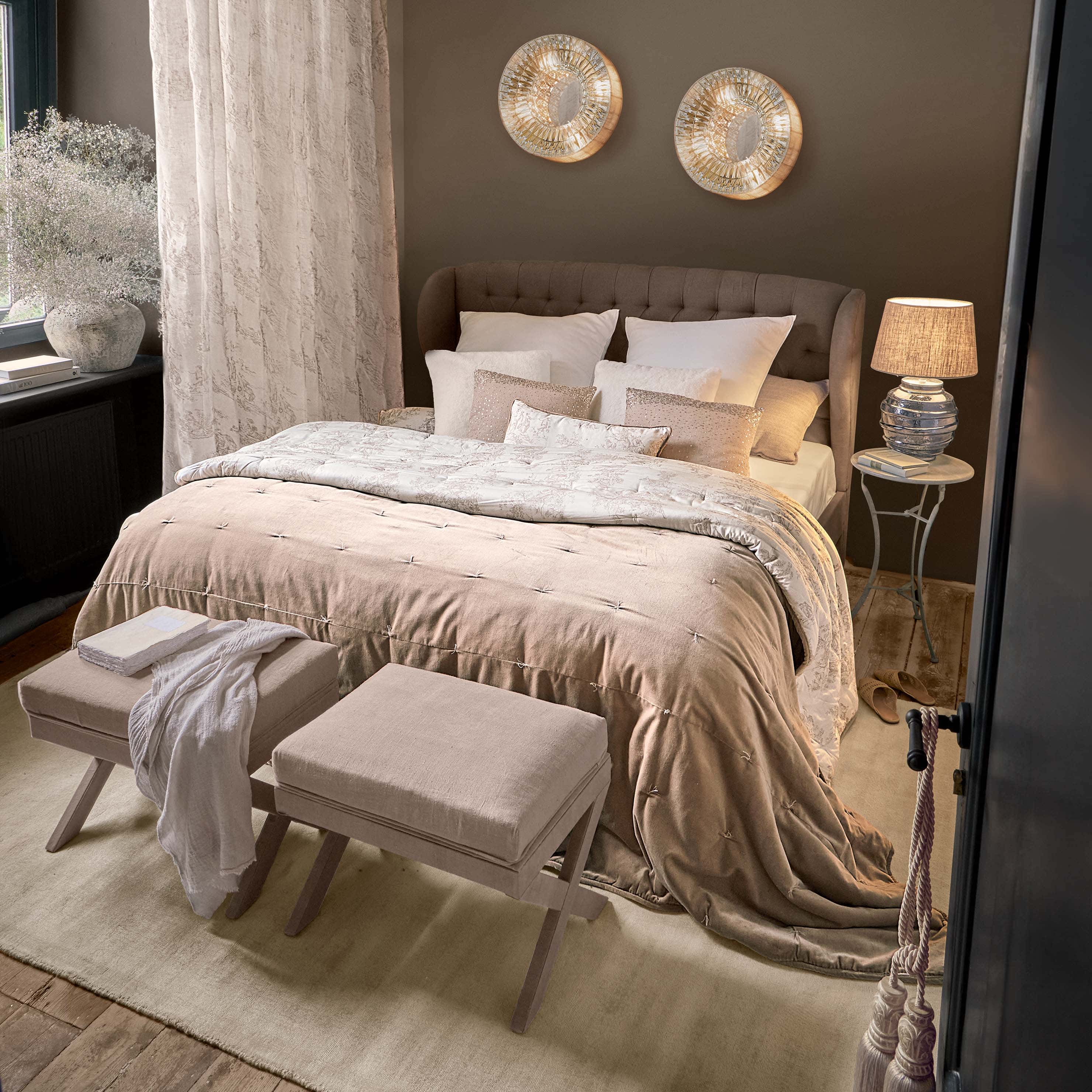 Gemütliches Schlafzimmer mit braunem Polsterbett und beiger Bettwäsche mit dekorativen Kissen