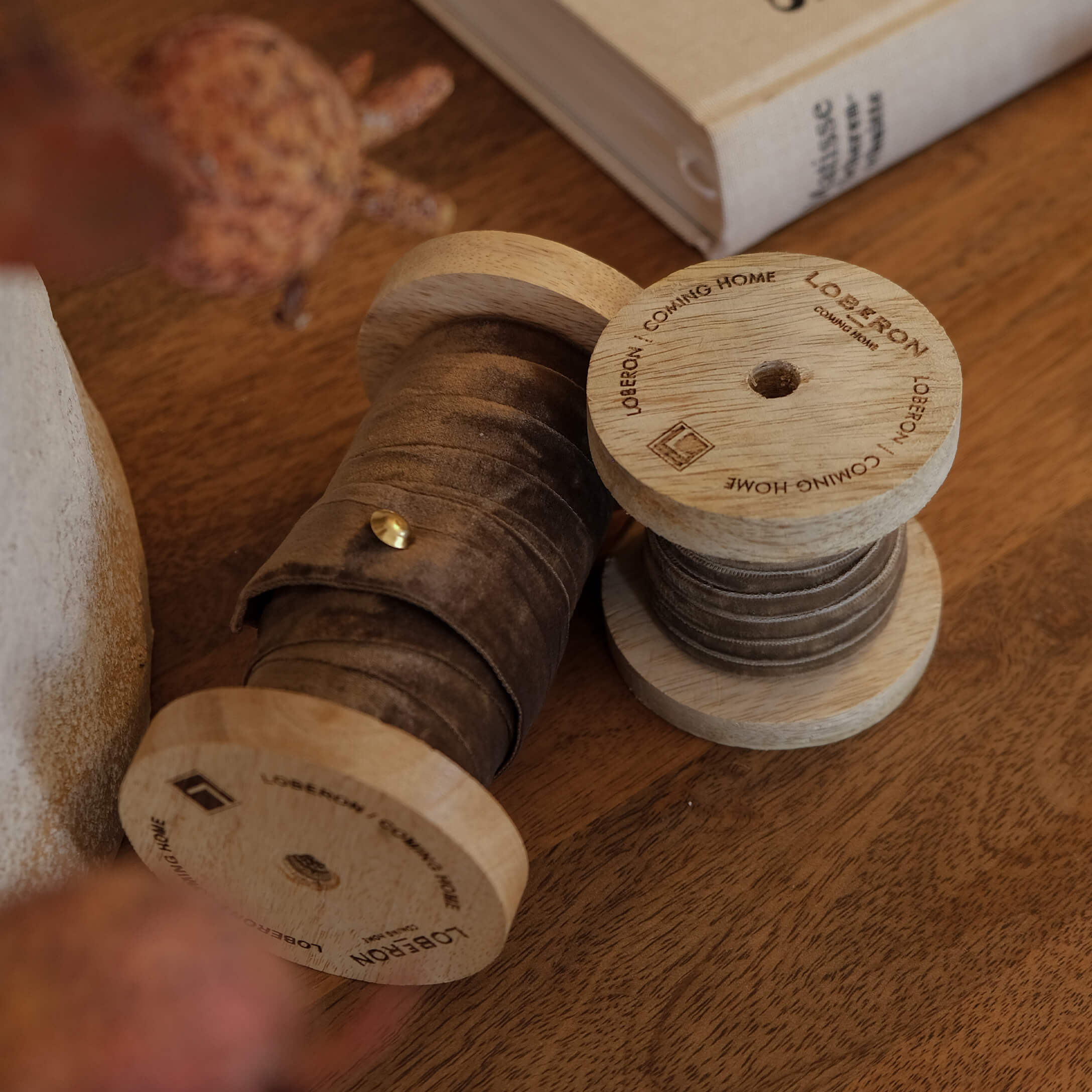 Holzspulen mit braunem Samtband auf Holztisch, dekoratives Wohnaccessoire