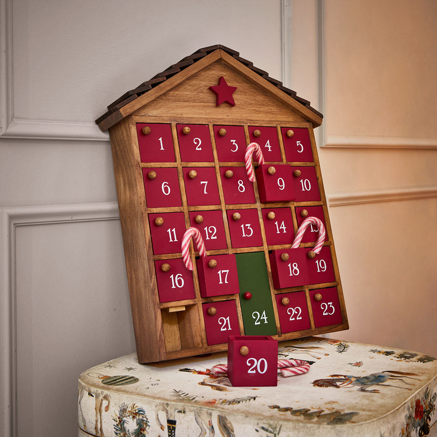 Holz-Adventskalender in Hausform mit roten Türen und grünem Türchen 24, dekoriert mit Zuckerstangen