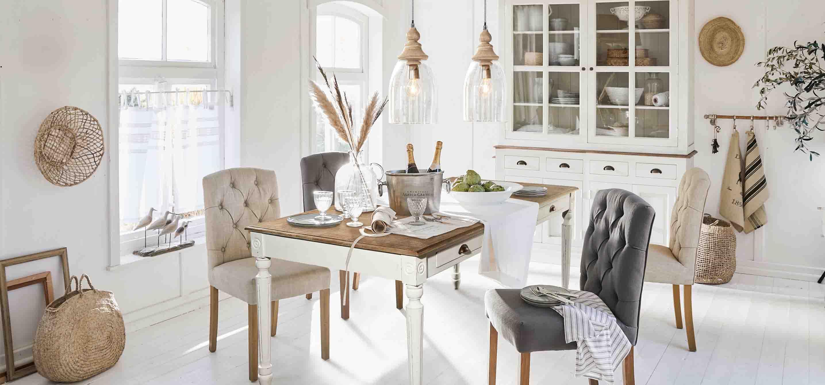 Rustikaler Essbereich mit weißem Holztisch und gepolsterten Stühlen in Beige und Grau in hellem Raum