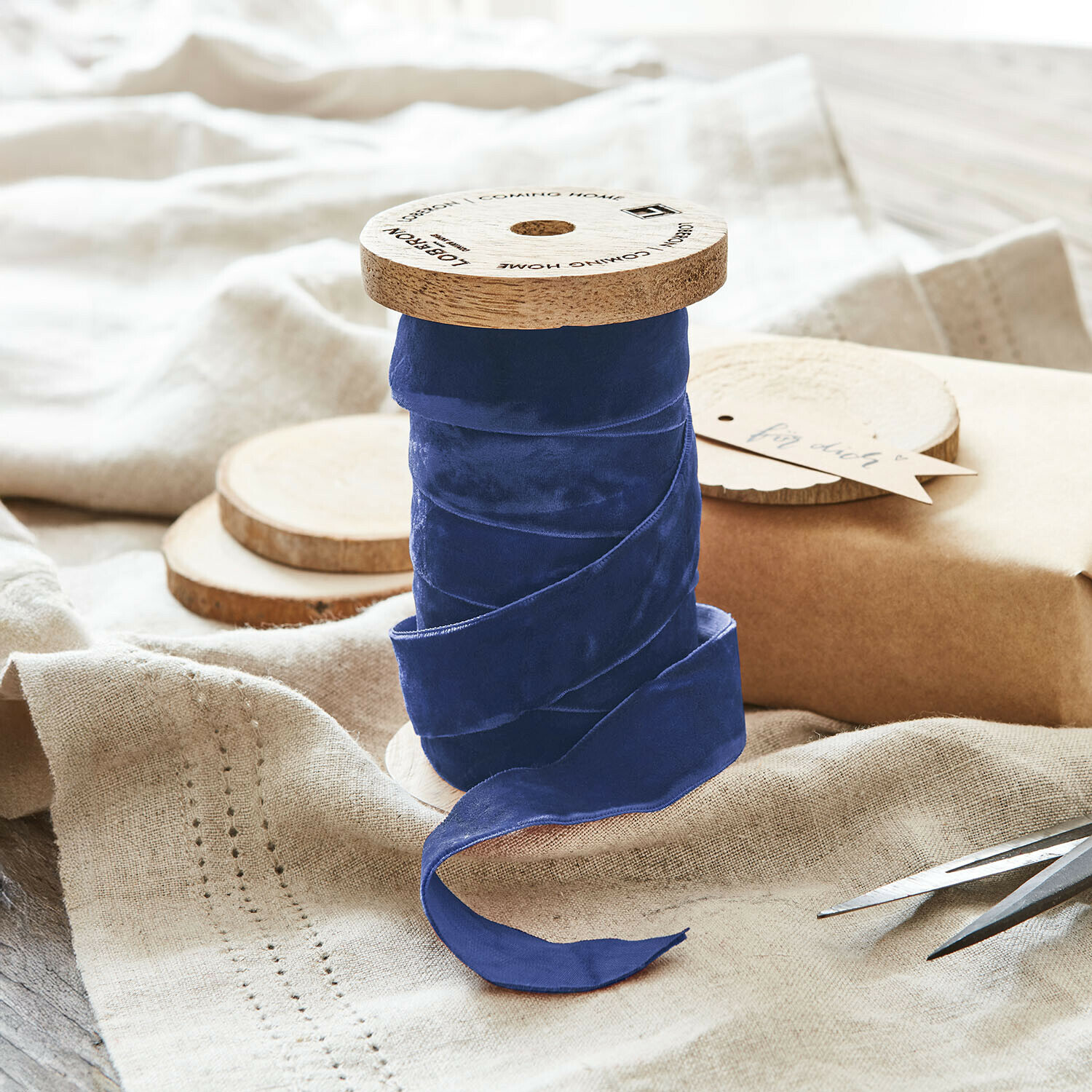 Samtband Andaris Dunkelblaue Samtschleife auf Holzspule auf naturfarbenem Leinenstoff für Dekoration und Basteln