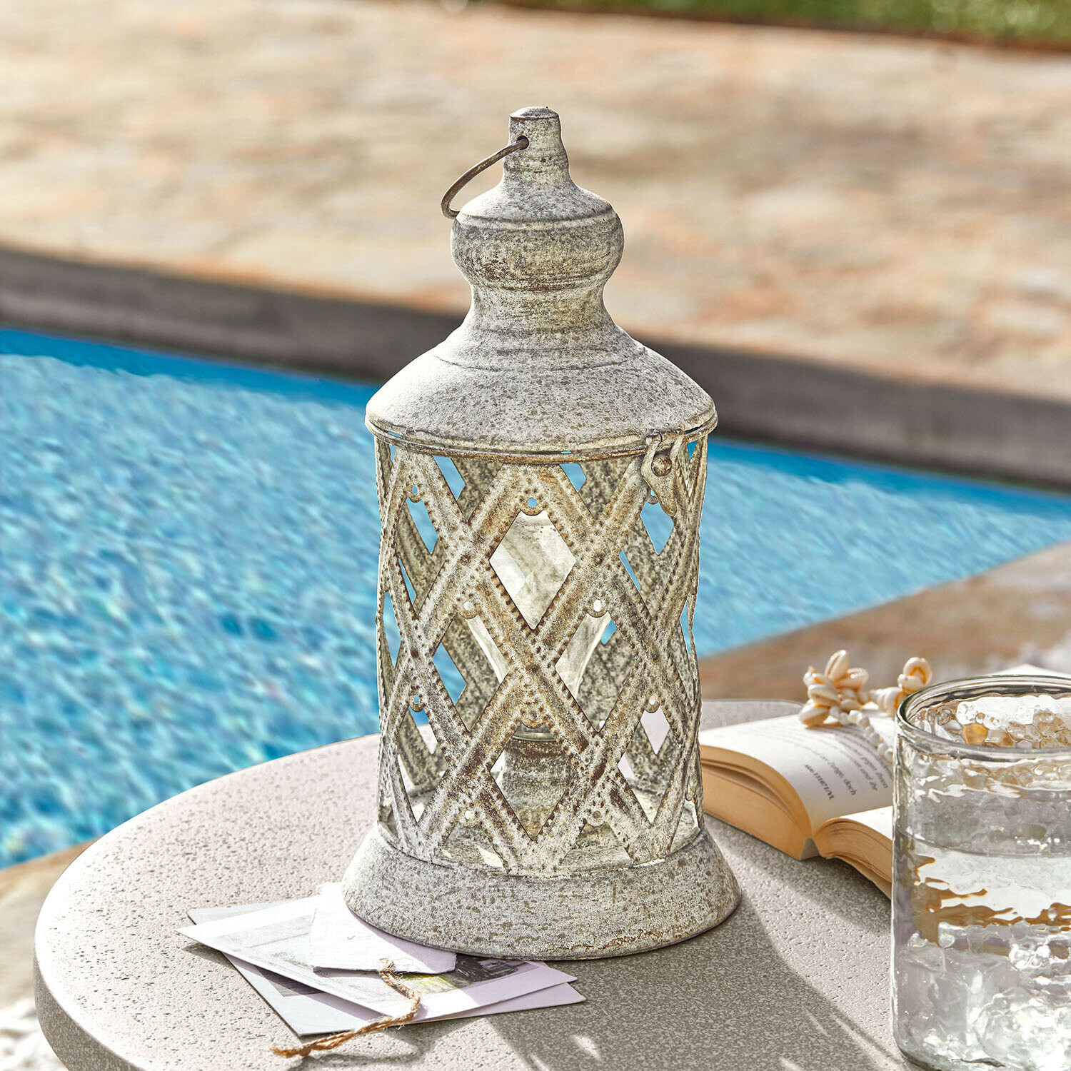 LED-Laterne Lavorie Dekorative Metalllaterne in antik-silber auf Tisch am Pool mit Buch und Wasserglas