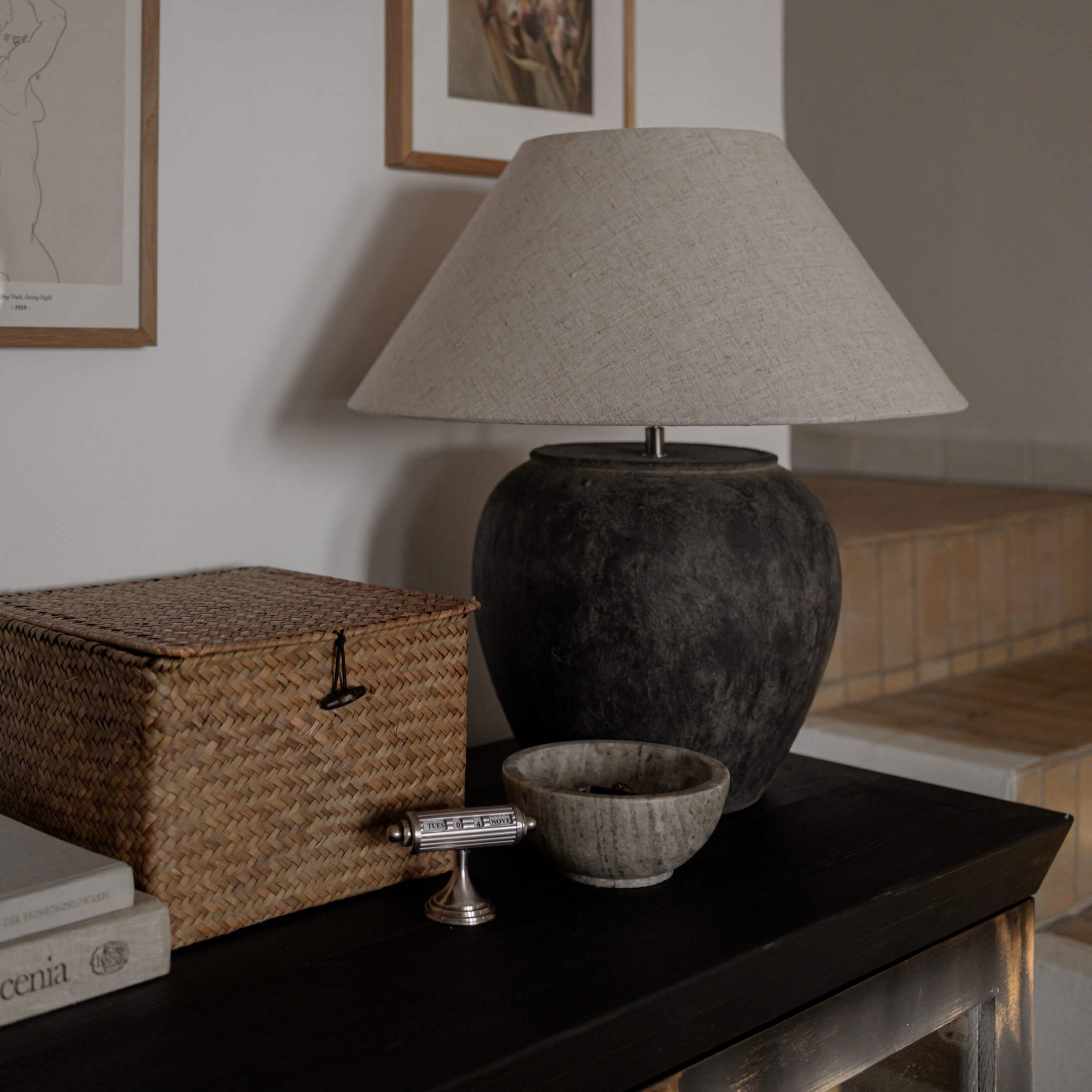 Tischlampe mit schwarzer Keramikbasis und beigem Lampenschirm auf dunklem Tisch im Wohnzimmer