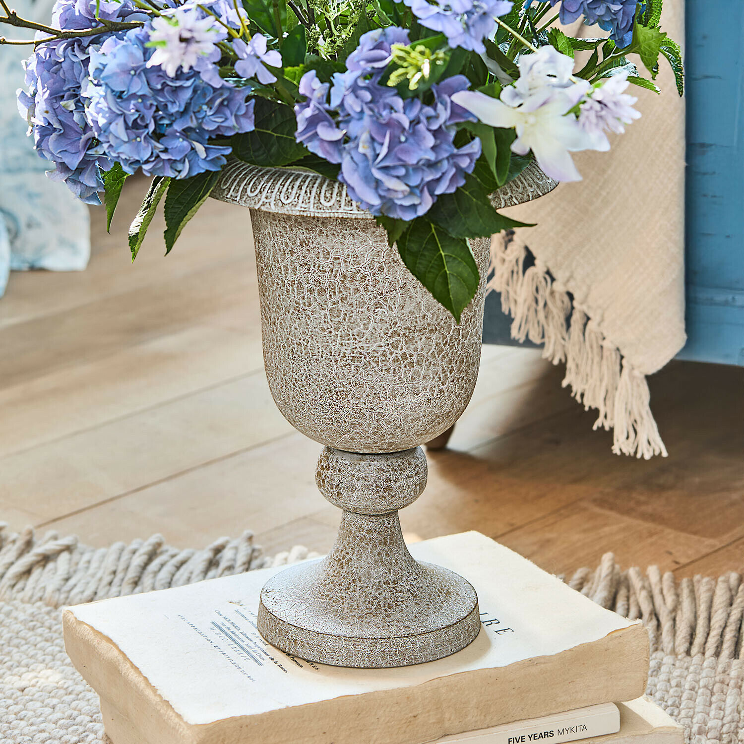 Vase Vittoriane Dekorativer beige Keramikvase mit Patina und blauen Blumen auf alten Büchern arrangiert
