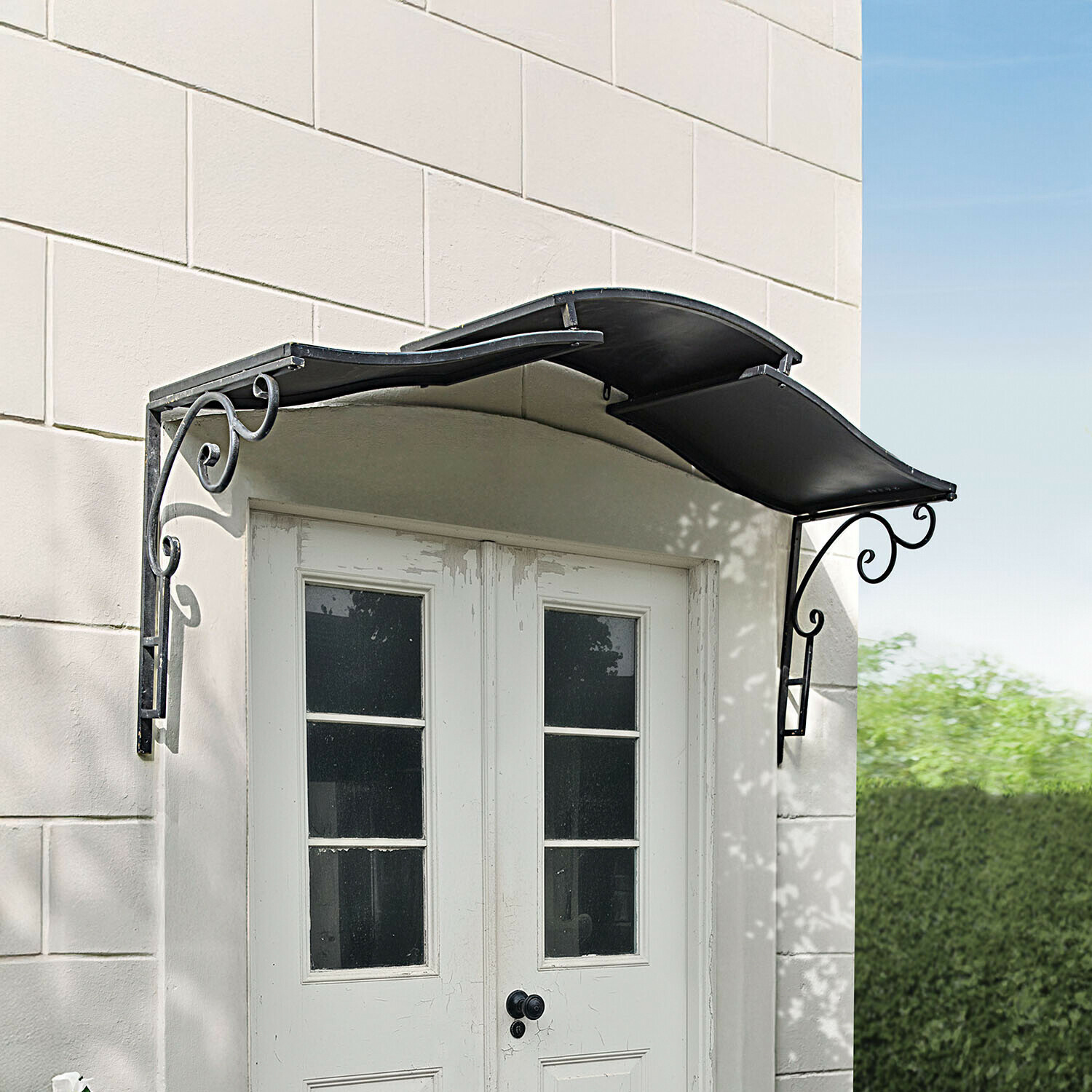 Schwarzes Metallvordach mit dekorativen Halterungen über weißen Doppeltüren mit Fenstern