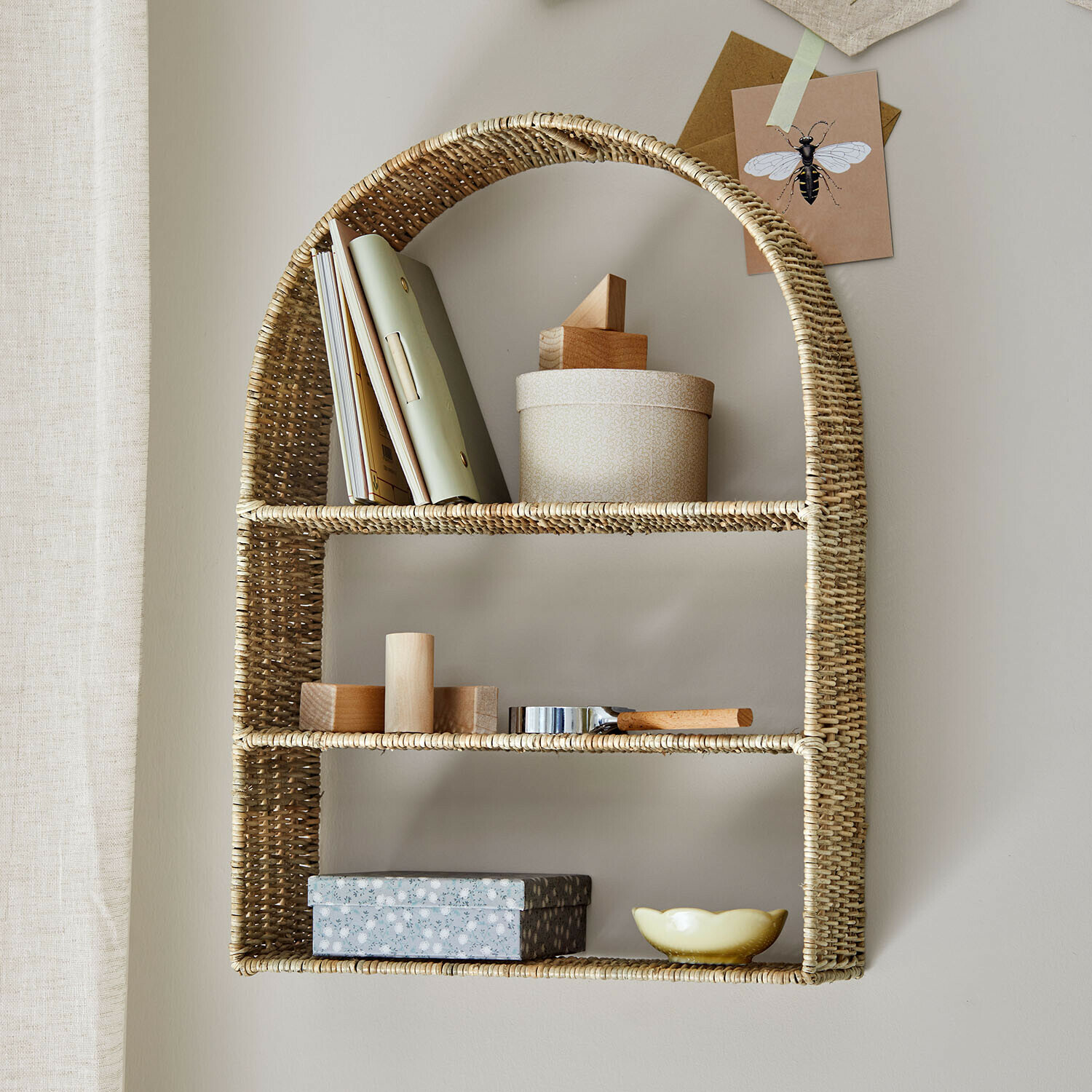 Wandregal aus natürlichem Rattan mit Dekorationen und Büchern zur Aufbewahrung