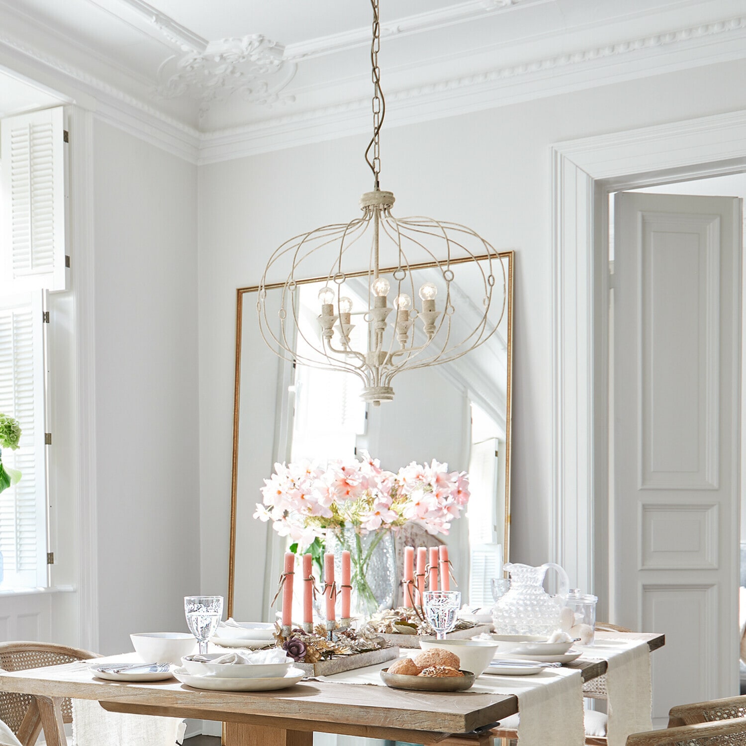 Leuchter Aragonese Heller Essbereich mit Holztisch, rosa Kerzen und vintage Metall-Kronleuchter über dem Tisch