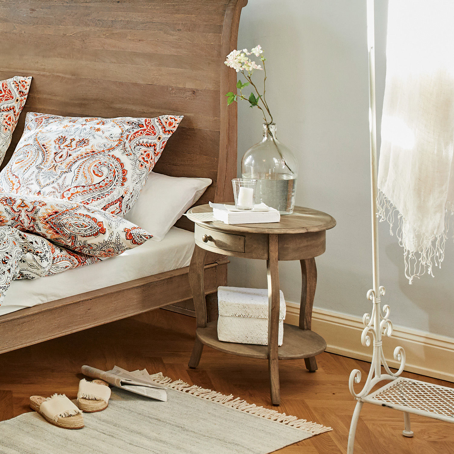 Runder Nachttisch aus Holz mit Schublade und Ablage in hellem Schlafzimmer mit Dekoration