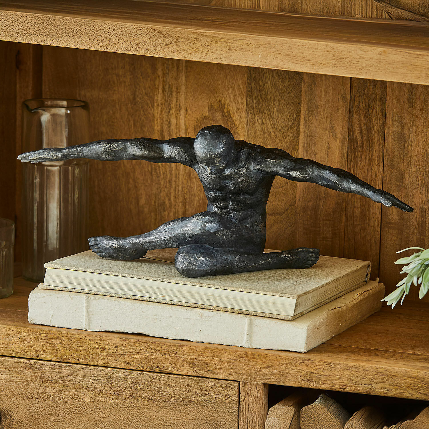 Figur Smitty Schwarze Skulptur einer männlichen Figur mit ausgestreckten Armen auf Büchern auf einem dekorativen Holzregal