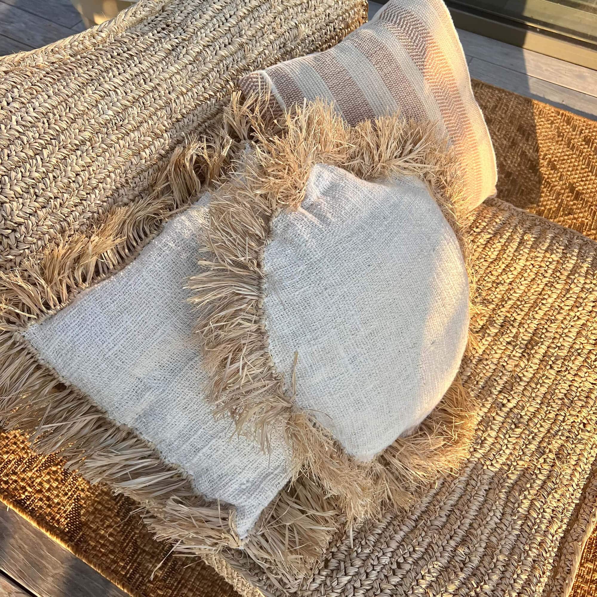 Natürliche Dekokissen mit Fransen auf beige geflochtenem Sitz, Boho-Stil und gemütliche Atmosphäre