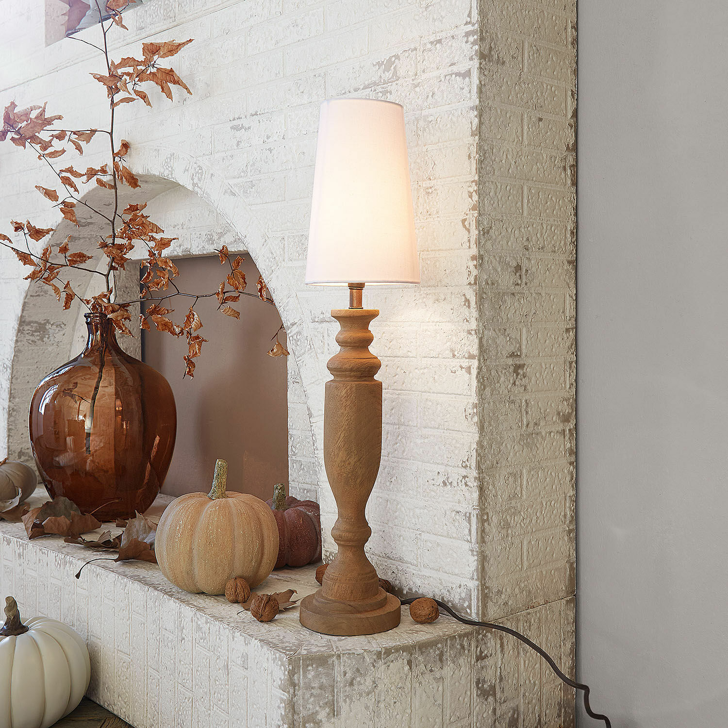 Tischlampe Ambrevaux Holz-Tischlampe mit weißem Lampenschirm vor weißer Ziegelwand und herbstlicher Dekoration