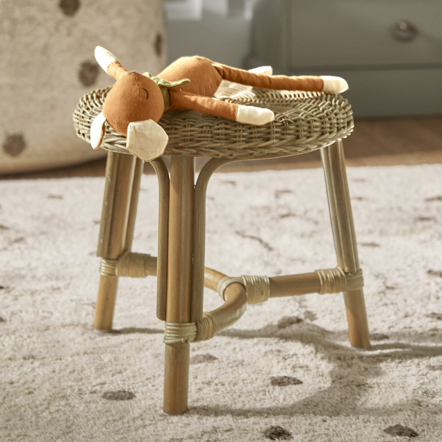 Hocker Dunley Rattanhocker in Naturfarbe mit Plüschtier auf weichem Teppich im Kinderzimmer