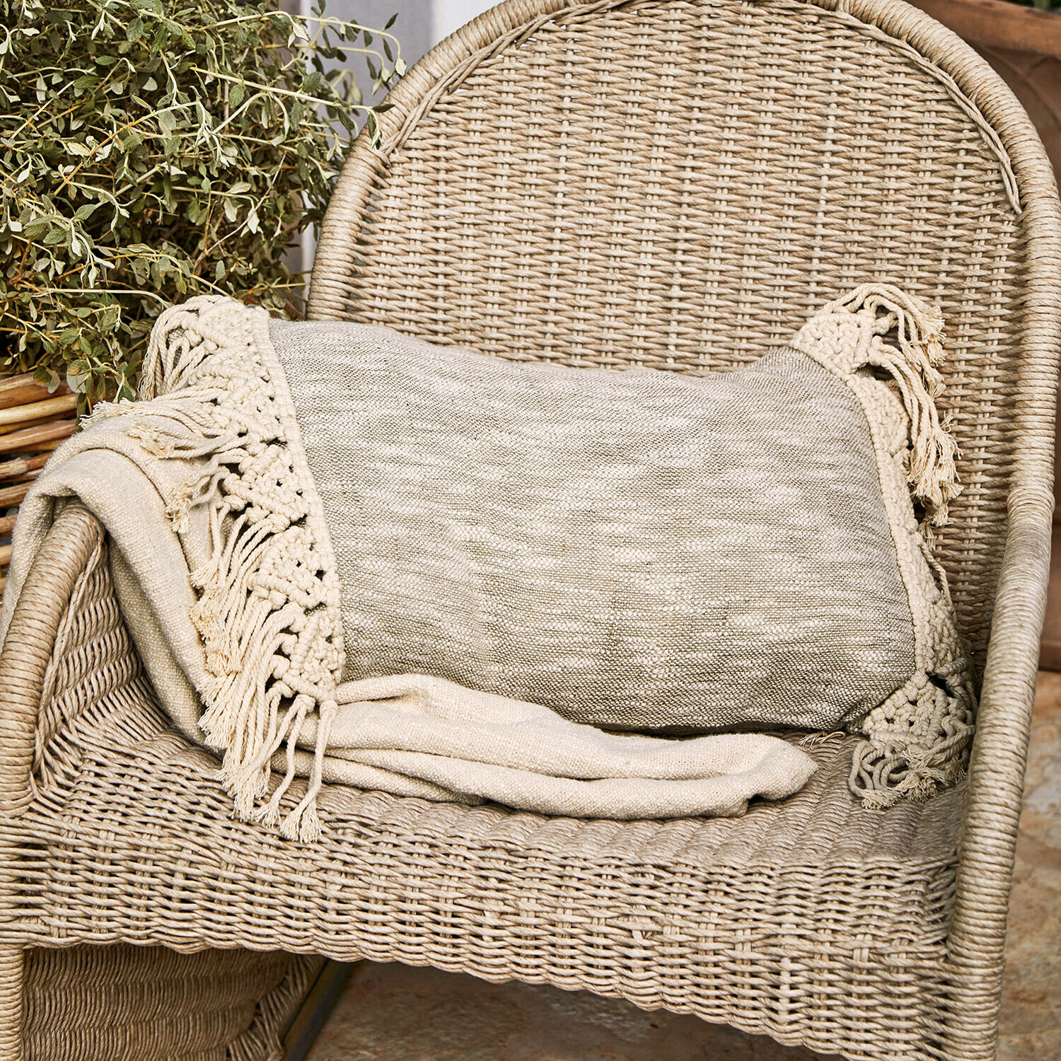Kissenhülle Dunlora Beige Decke mit Fransen auf einem Rattanstuhl, gemütliche Wohnraumdekoration und Textil