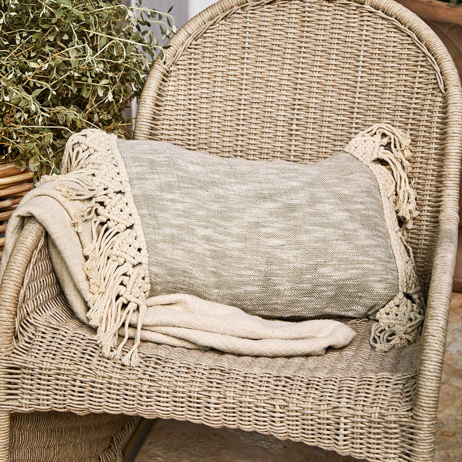 Kissenhülle Dunlora Beige Decke mit Fransen auf einem Rattanstuhl, gemütliche Wohnraumdekoration und Textil
