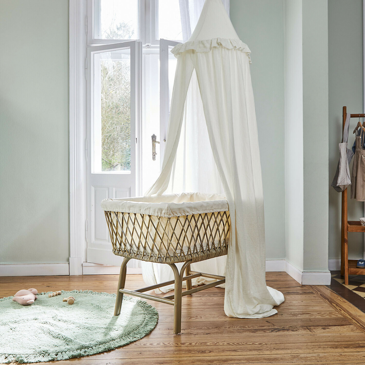 Kinderbett aus natürlichem Rattan mit weißem, leichtem Baldachin in hellem Kinderzimmer