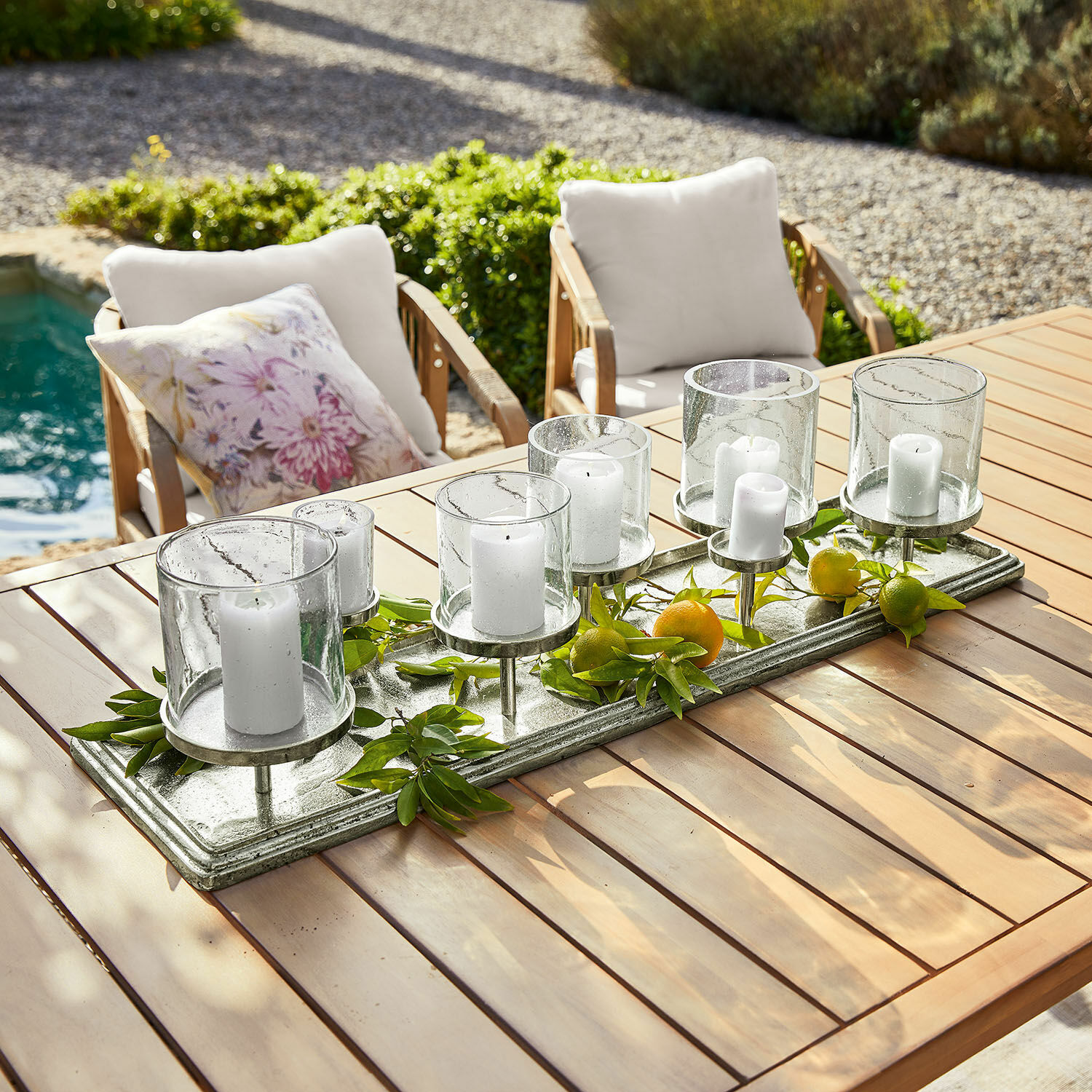 Kerzentablett Devonne Dekorativer Kerzenhalter aus Glas und Metall mit weißen Kerzen auf Holztisch im Garten