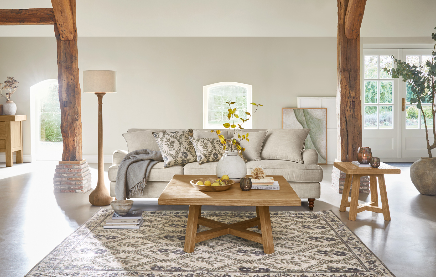 Gemütliches Landhaus-Wohnzimmer mit beigem Sofa, Holztisch und gemustertem Naturteppich