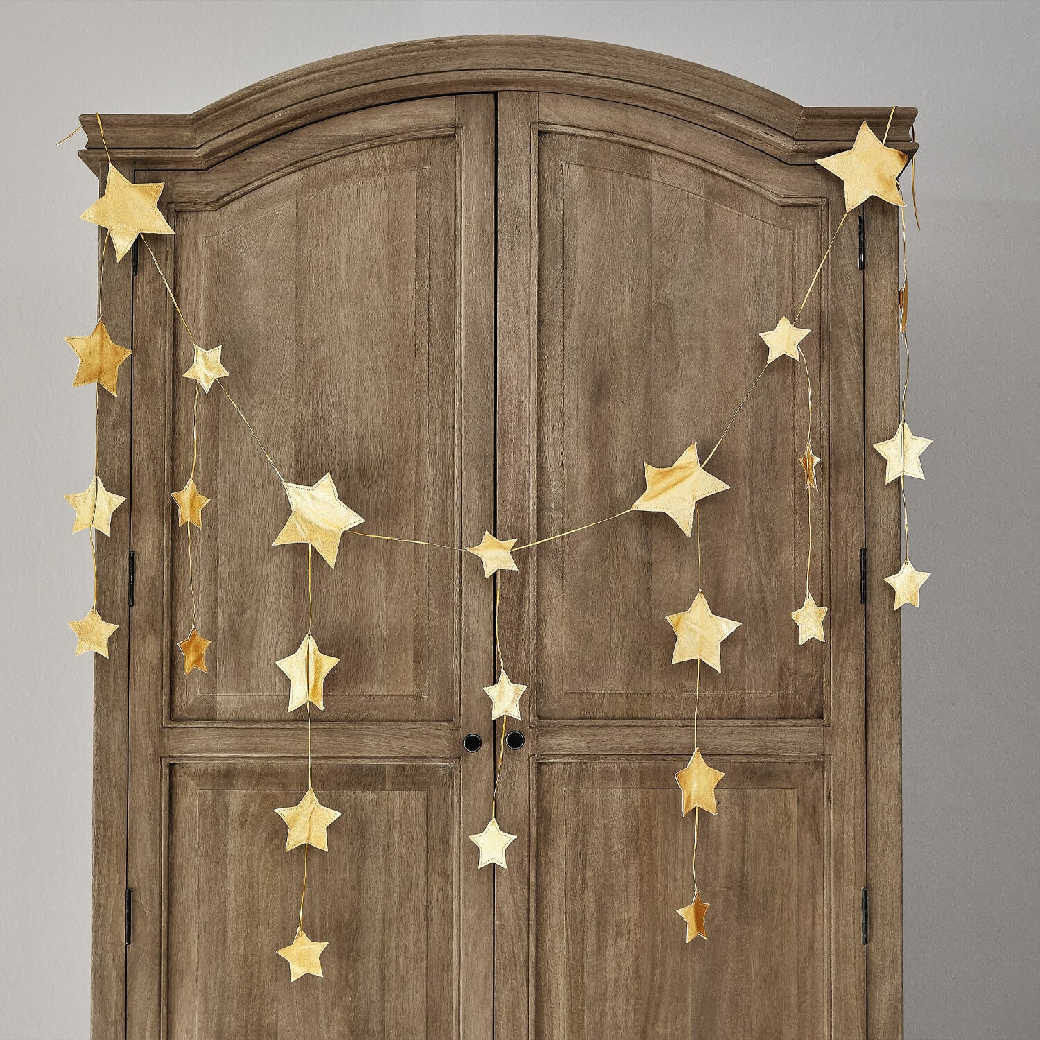 Girlande Étoilin Goldene Stern-Girlande an einem Holzschrank, festliche Wohnraumdekoration für Weihnachten