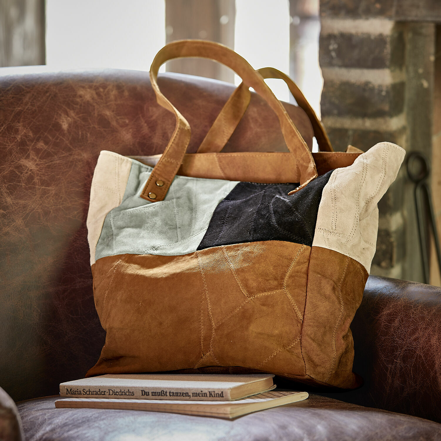 Tasche Quinvelle Patchwork-Tasche aus braunem, schwarzem und beigem Veloursleder auf braunem Ledersessel