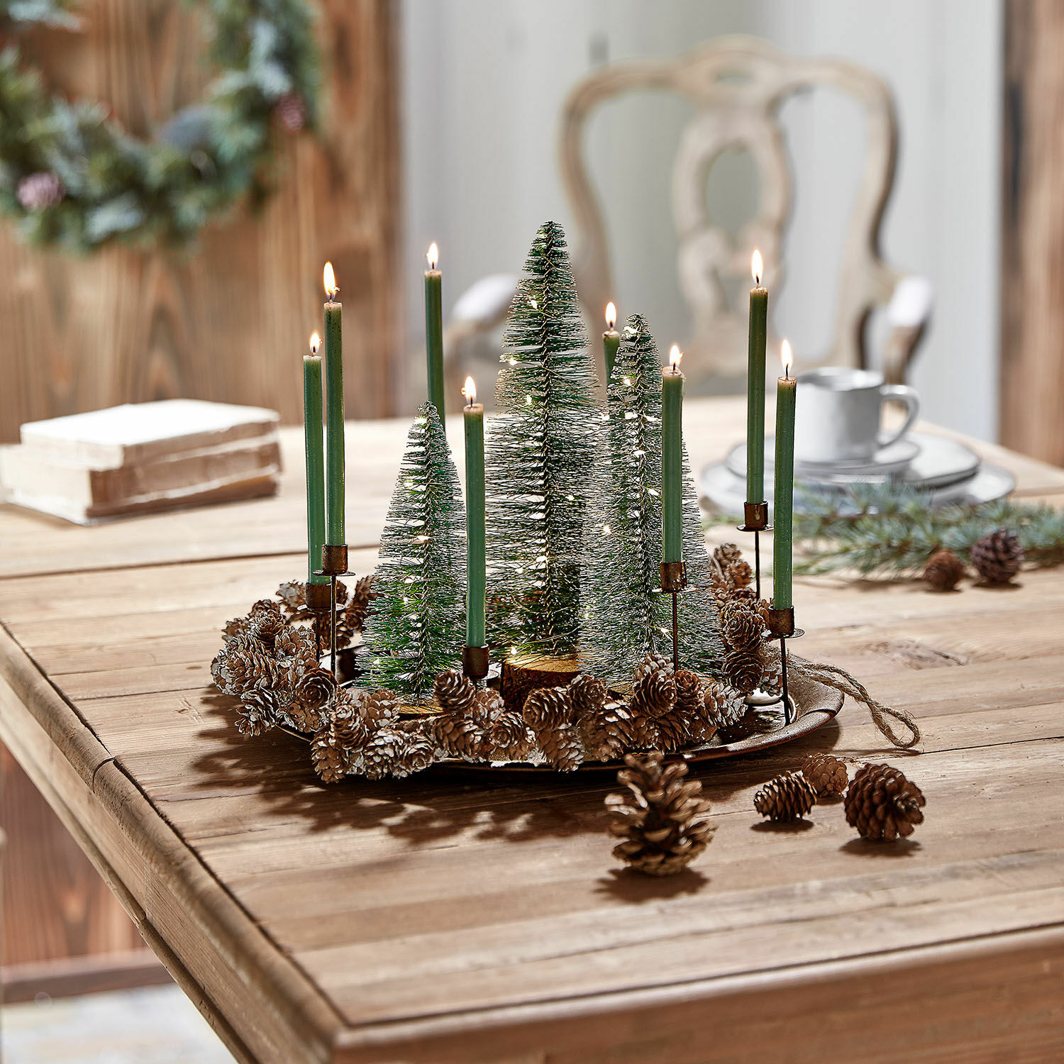 Weihnachtlicher Dekokranz mit grünen Kerzen und Tannenzapfen auf Holztisch