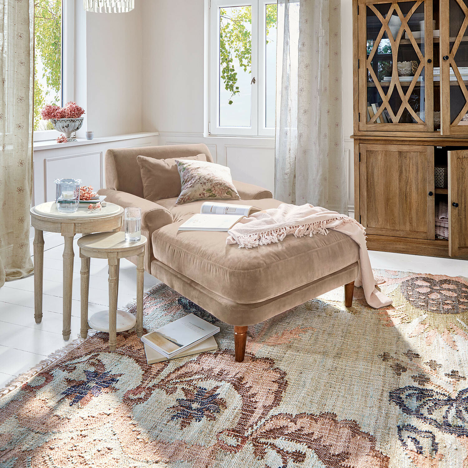Chaiselounge Jouvrelle Beige Samt-Chaiselongue mit Kissen und rosa Decke auf gemustertem Teppich in hellem Wohnzimmer