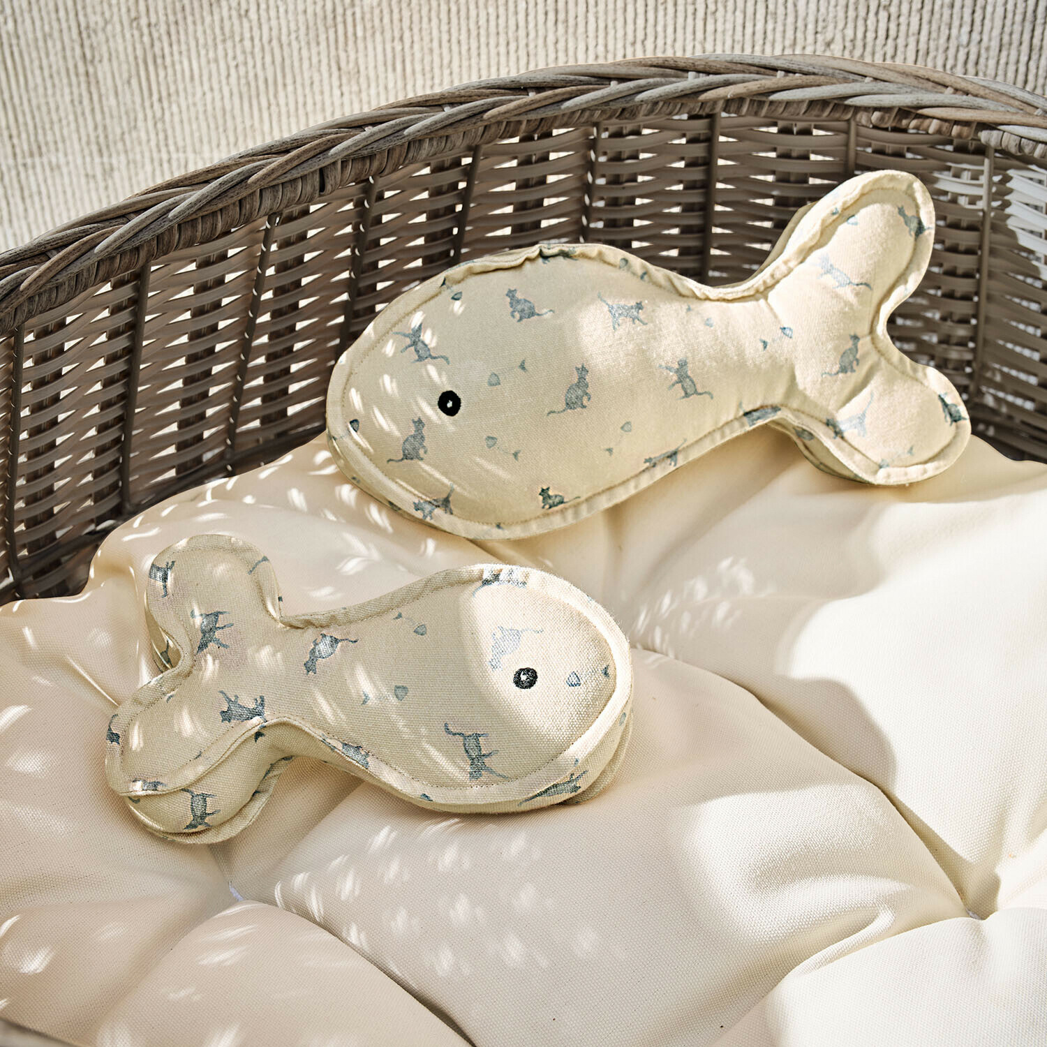 Beige Fischkissen mit Katzenmuster auf einem Rattansessel mit hellem Polster
