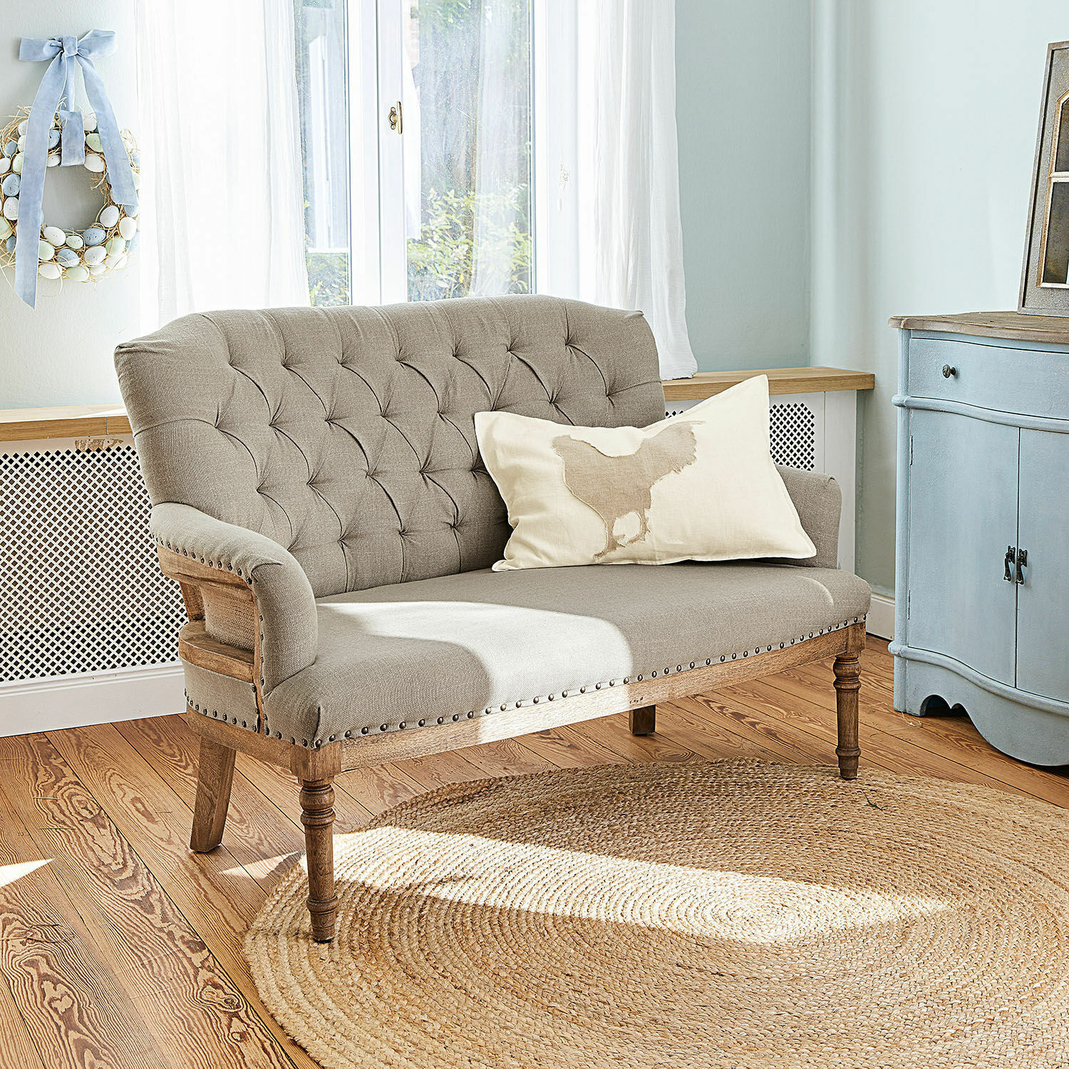 Sofa Kingsley Beiges, gepolstertes Sofa mit Holzrahmen und Zierknöpfen in hellem Wohnzimmer