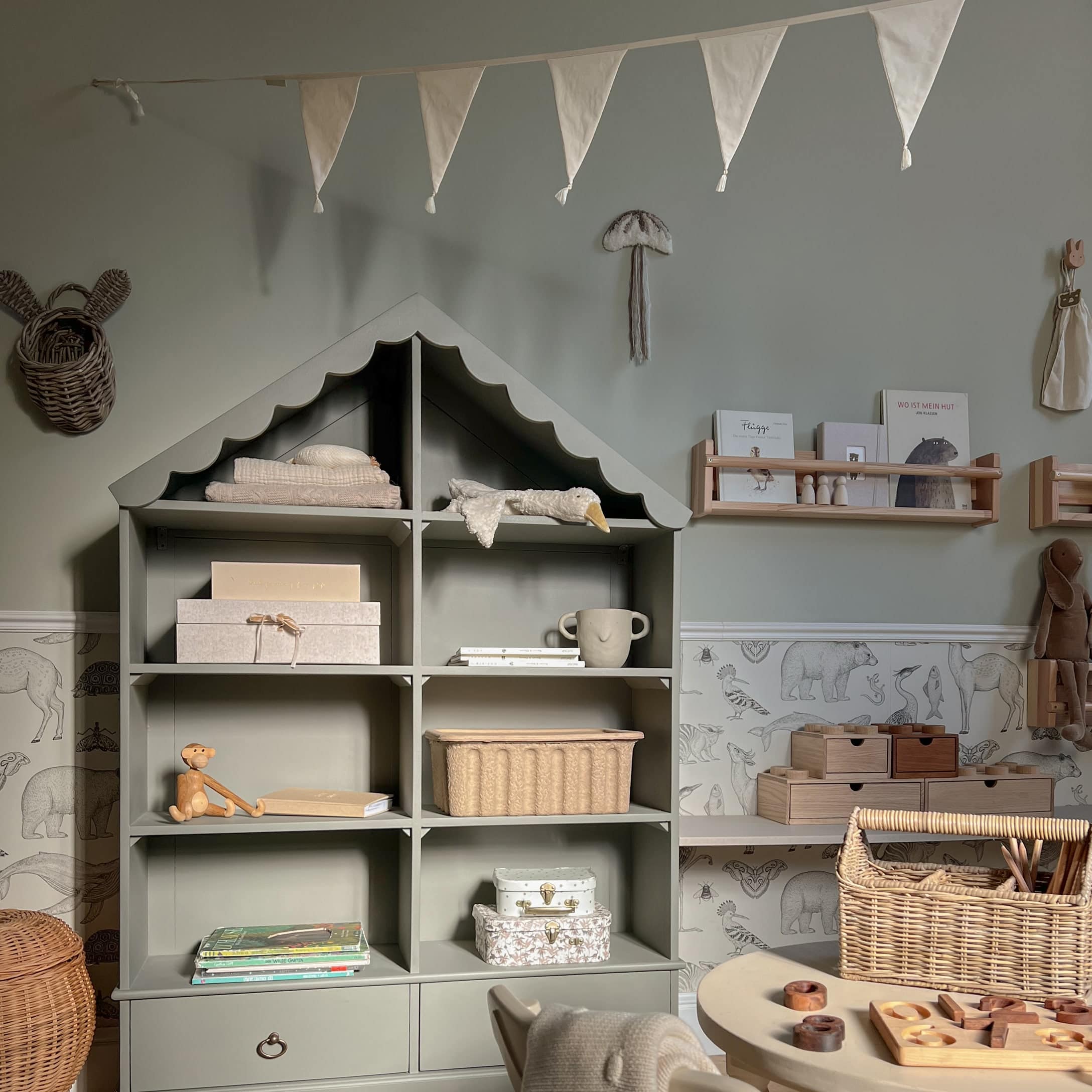 Graues Holzregal in Hausform mit Dekorationen und Spielzeug im Kinderzimmer