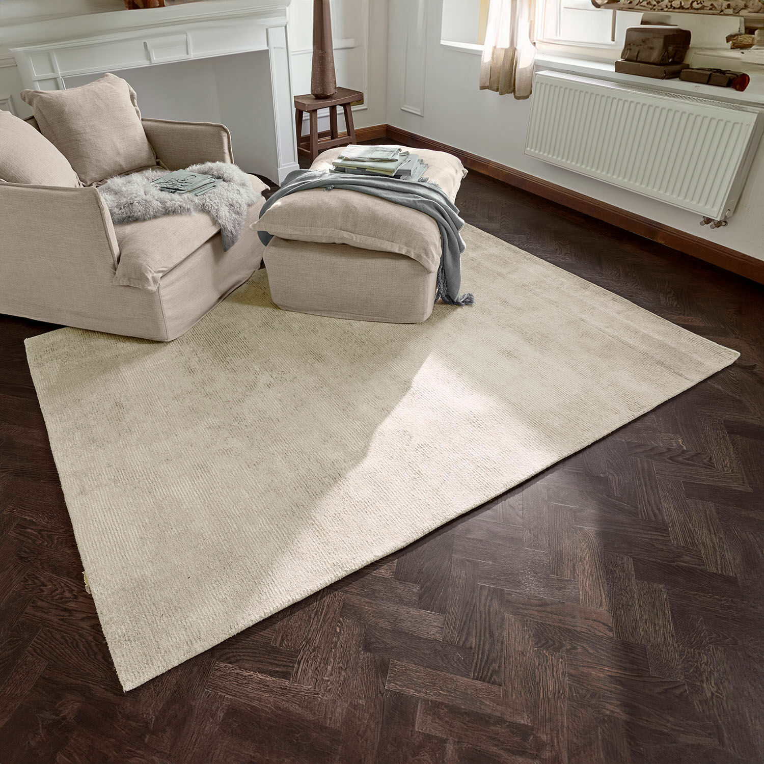 Beiger Teppich aus weichem Material auf dunklem Holzboden in hellem Wohnzimmer mit Sessel