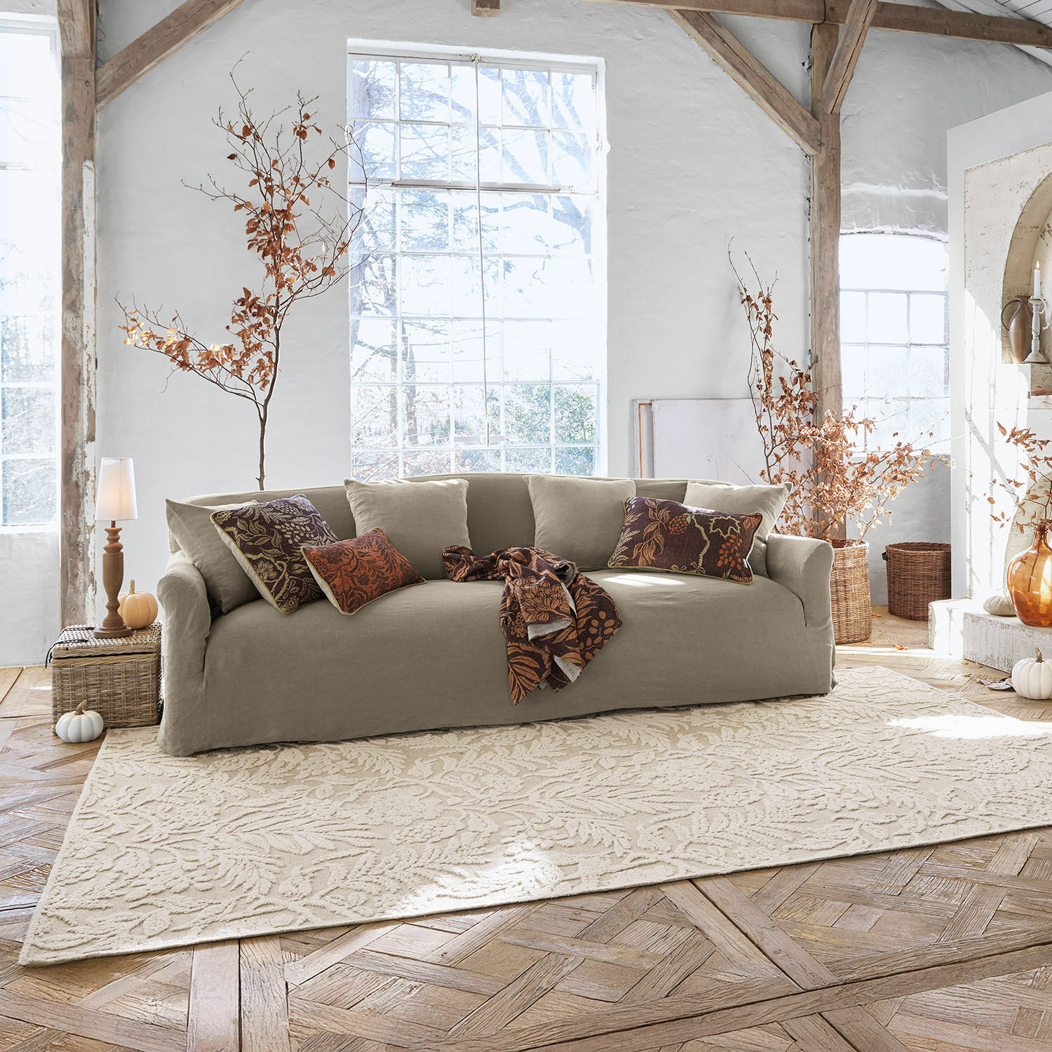 Teppich Azimra Beige Stoffsofa mit dekorativen Kissen und Decke in hellem, gemütlichem Wohnzimmer