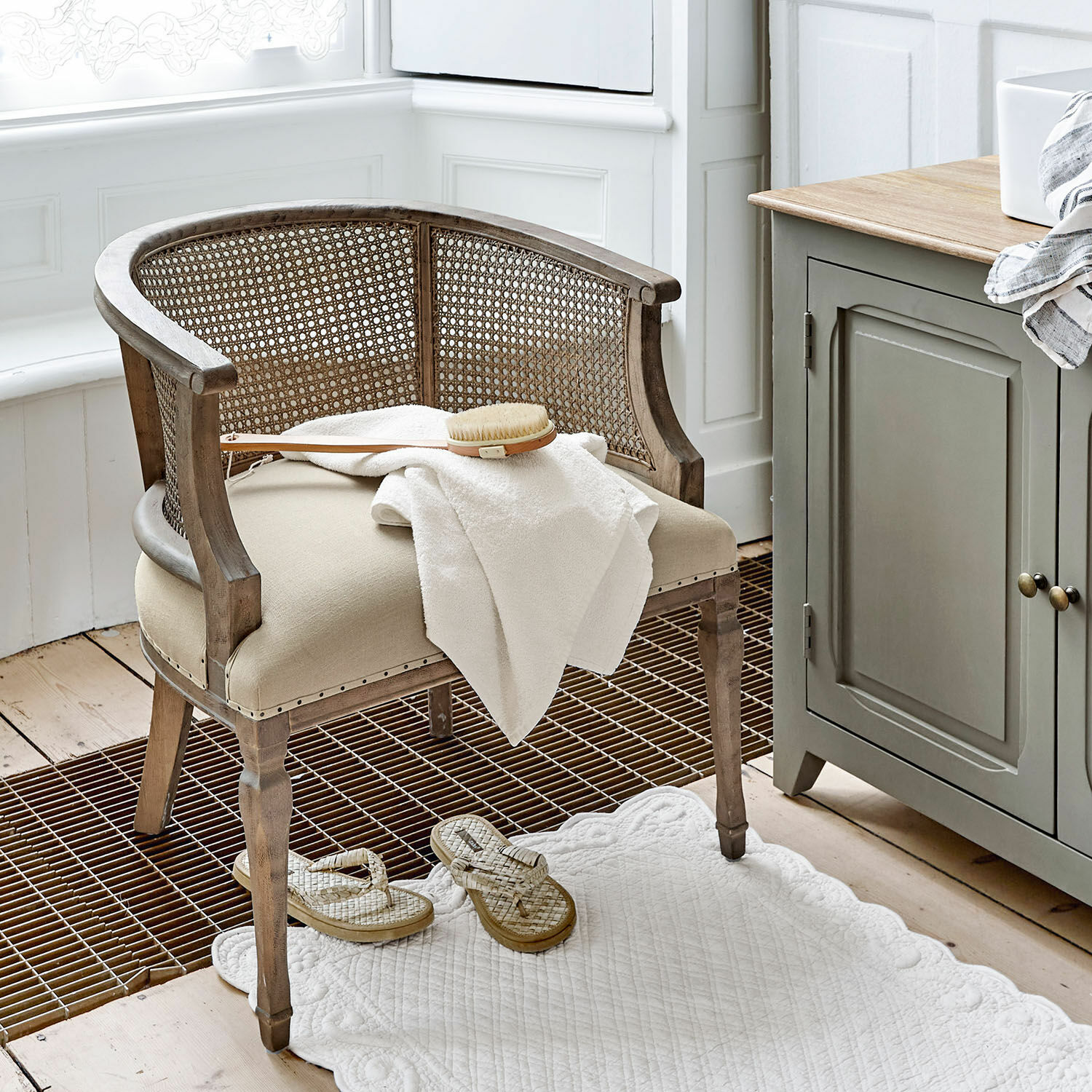 Stuhl Curbigny Stuhl aus Holz und Rattan in Beige mit gepolstertem Sitz und weißem Handtuch im Badezimmer