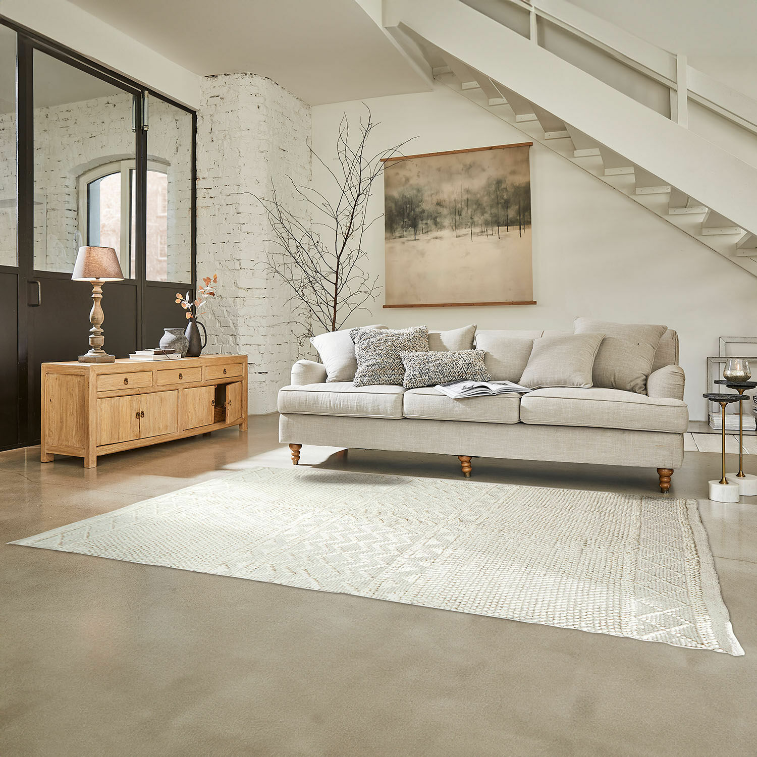 Teppich Hadir Beige Sofa mit Kissen und hellem Holzsideboard im hellen Wohnzimmer mit Teppich und Wandbild