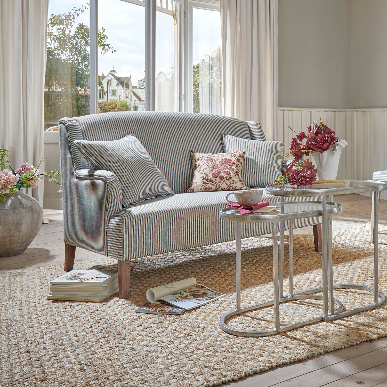 Gestreiftes Sofa aus grauem Stoff mit Kissen und Metall-Couchtischen in hellem Wohnzimmer