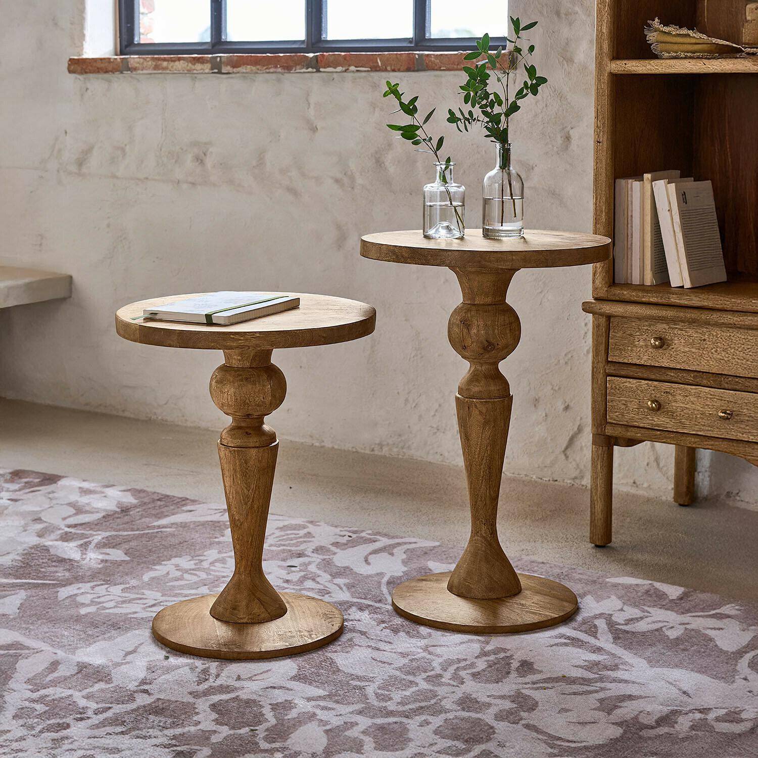 Zwei runde Beistelltische aus Mangoholz in Naturfarbe auf gemustertem Teppich