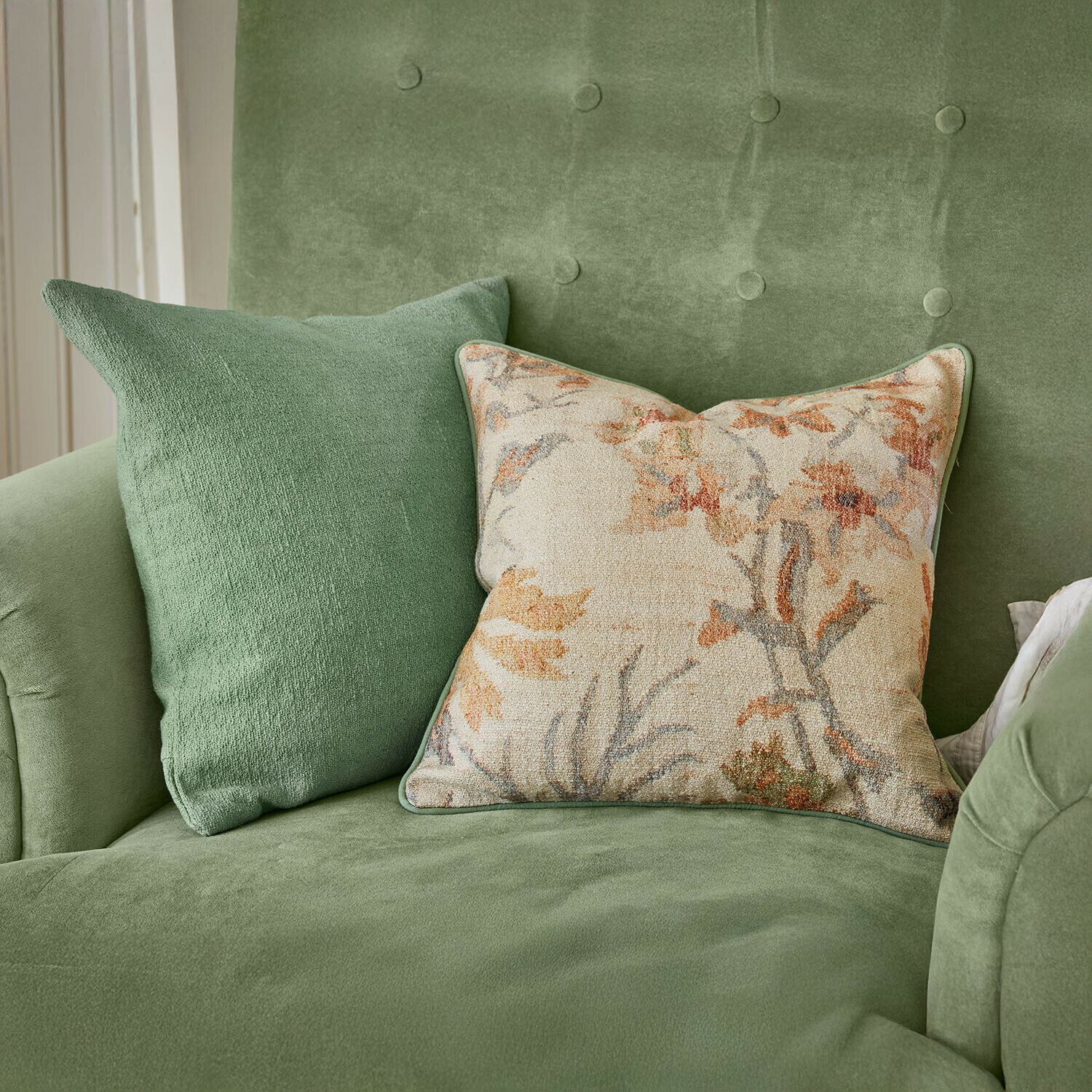 Grünes Samtsofa mit zwei Kissen, einfarbig und floral gemustert, stilvolle Wohnzimmerdekoration