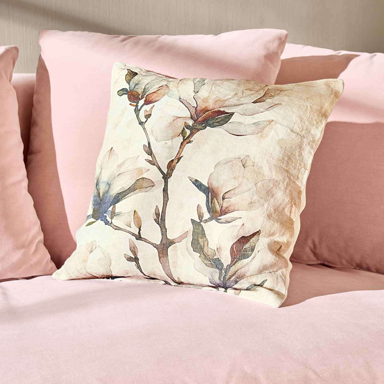 Dekoratives Baumwollkissen mit Blumenmuster auf rosa Sofa, stilvolles Wohnaccessoire