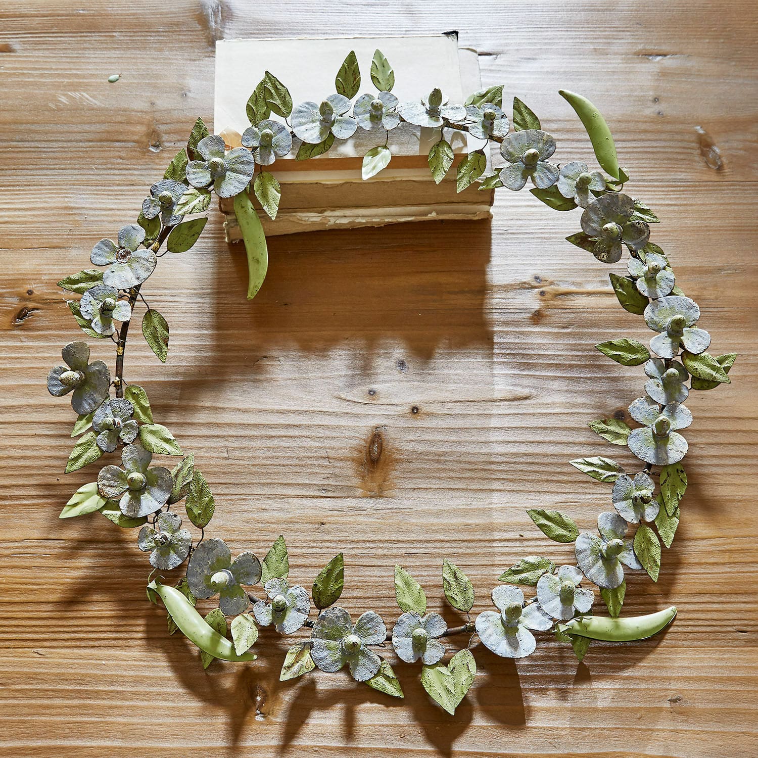 Kranz Cecilia Metallkranz mit grünen Blättern und weißen Blüten auf Holztisch als Dekoration