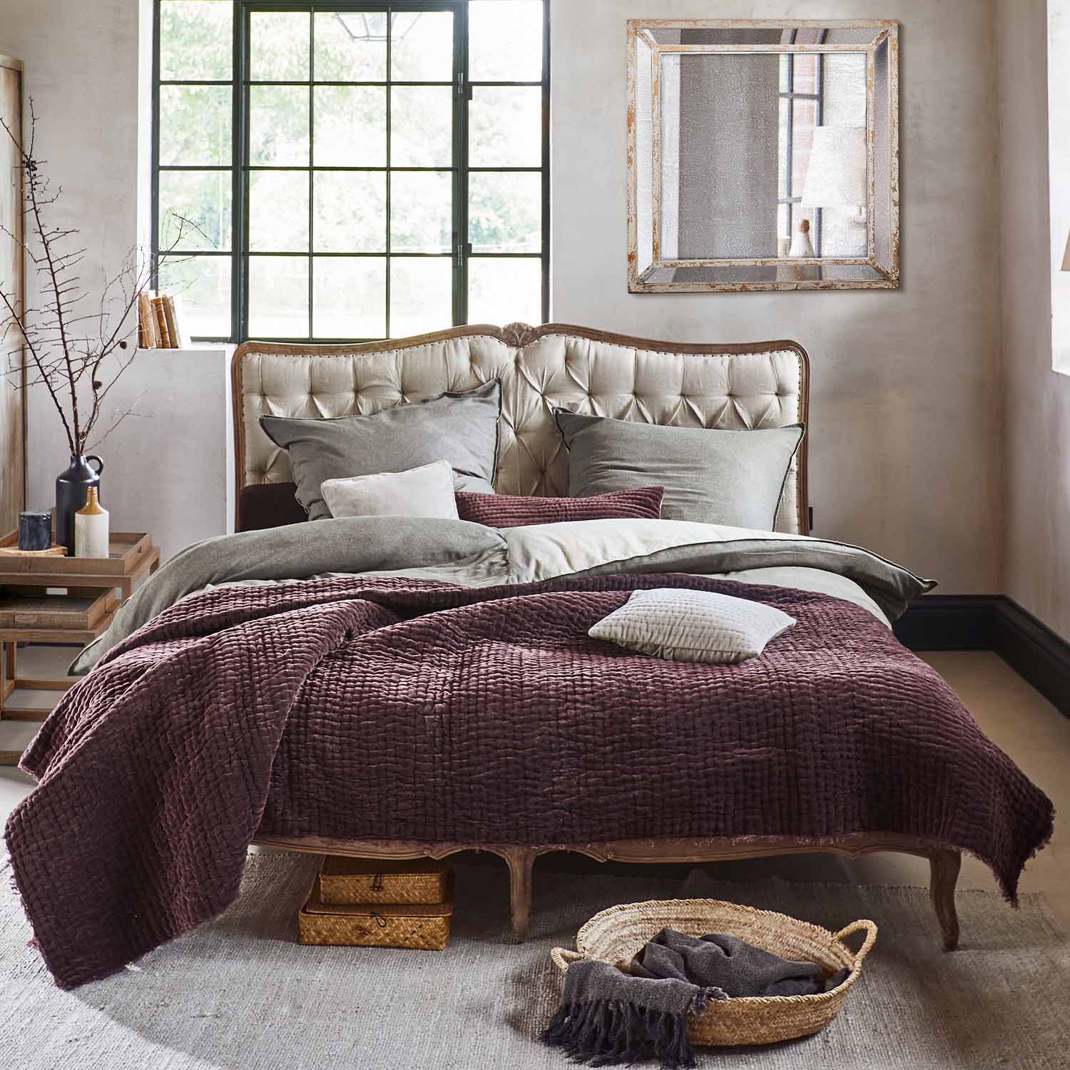 Bett mit beigem, gepolstertem Kopfteil und weicher, bordeauxfarbener Tagesdecke im Vintage-Stil