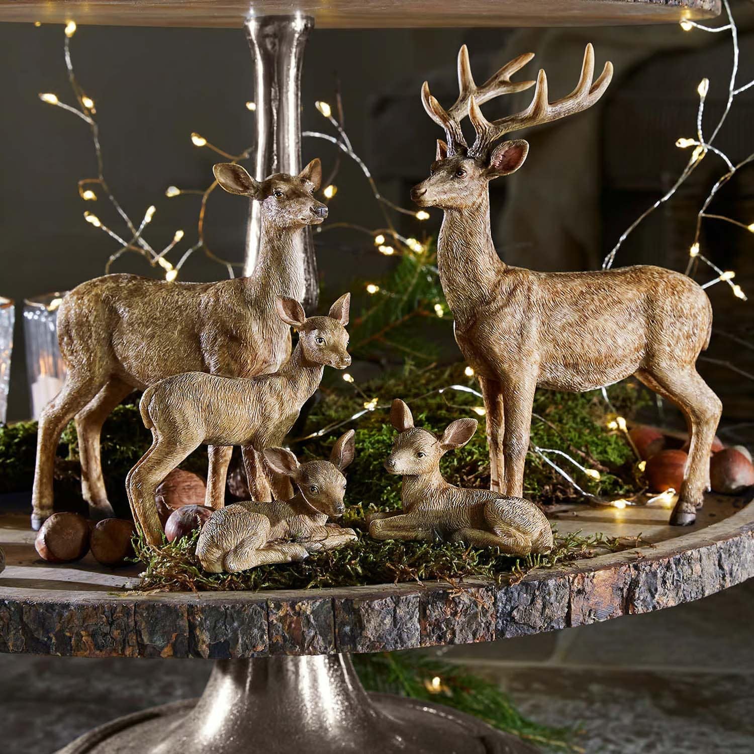 Dekoratives Set aus braunen Hirschfiguren aus Kunststoff auf rustikalem Holztablett für Wohnräume