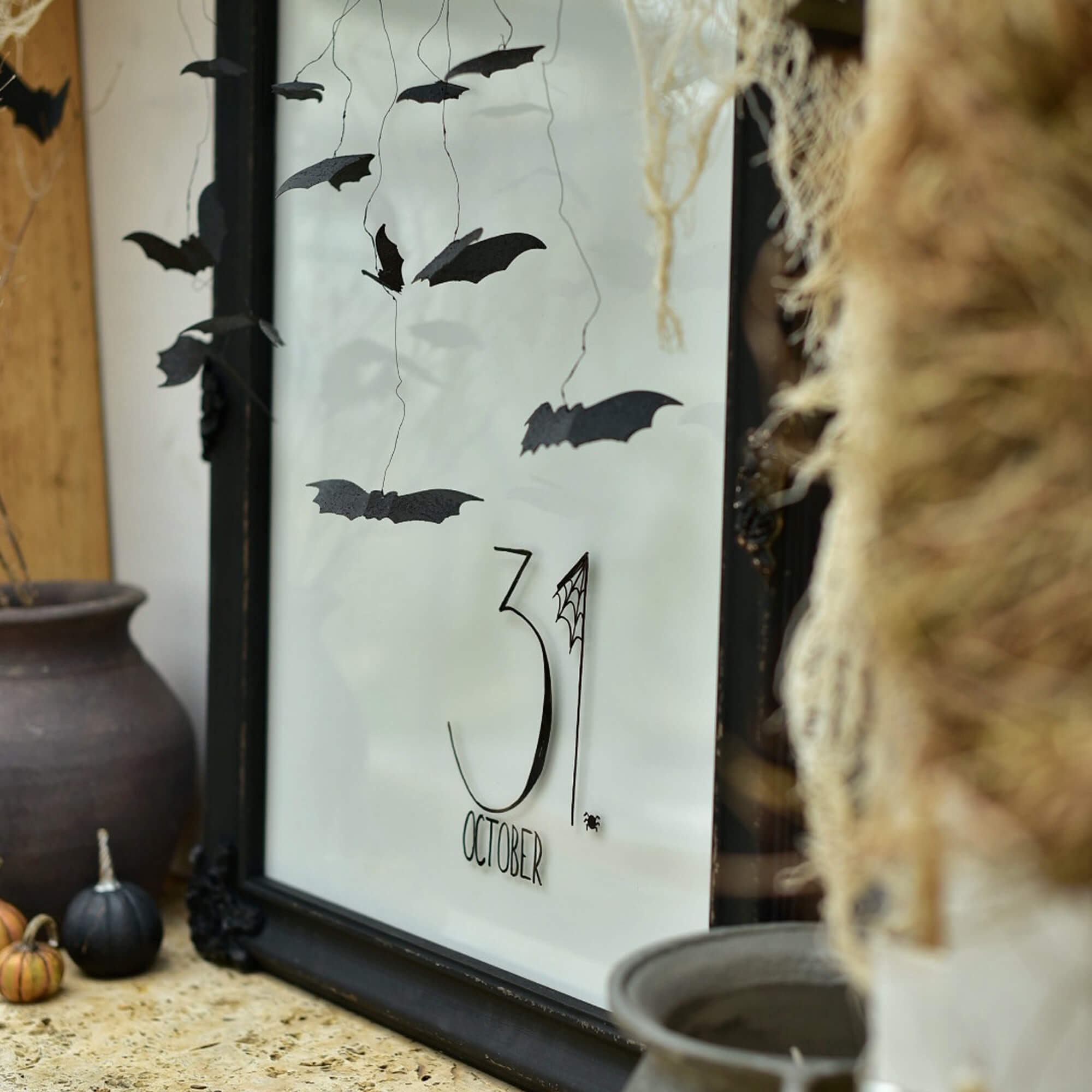 Halloween-Dekoration mit schwarzen Papierfledermäusen und Schriftzug 31. Oktober im Rahmen