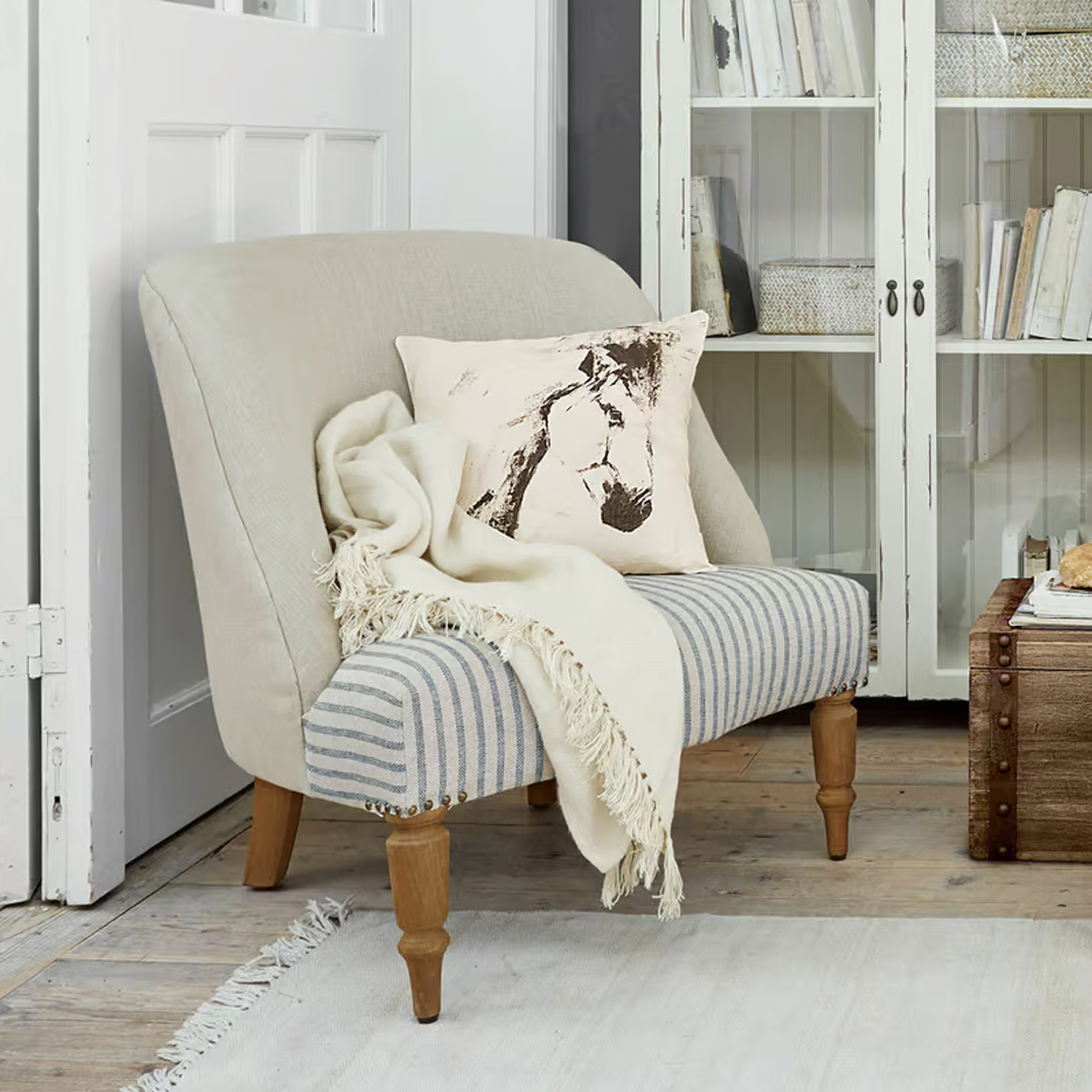 Zweisitziges Sofa mit gestreiftem Stoff, Holzbeinen, Pferde-Kissen und cremefarbenem Plaid im Wohnzimmer