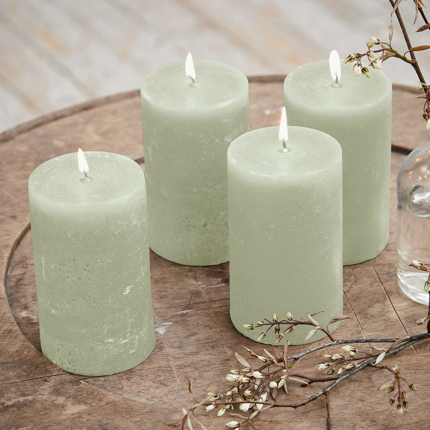 Kerze 4er Set Braga Set aus vier grünen Wachskerzen auf Holztisch mit floraler Dekoration