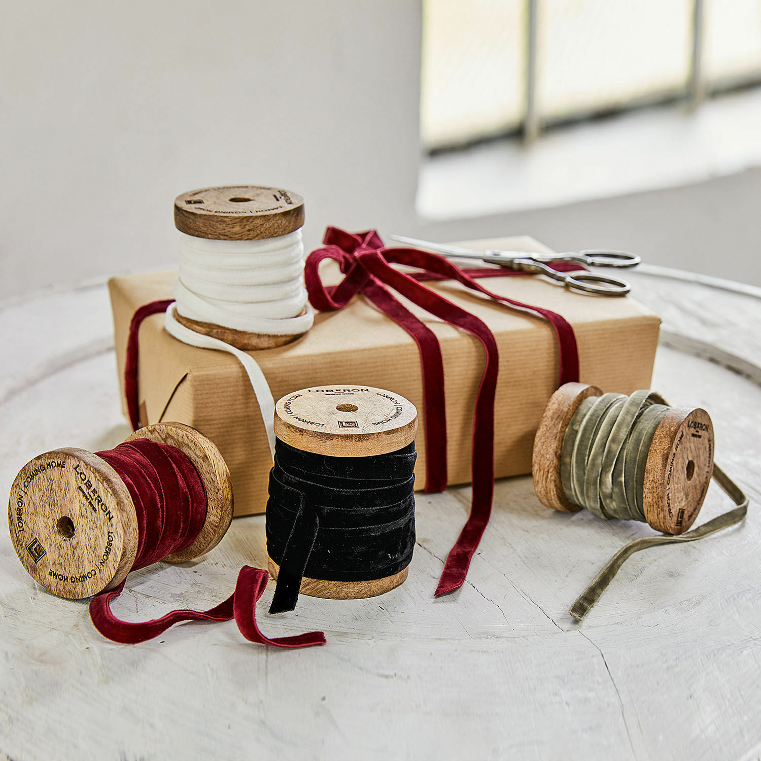Samtband 4er Set Hilary Set aus Holzspulen mit Samtbändern in Weiß, Rot, Schwarz und Oliv auf Tisch mit Geschenk