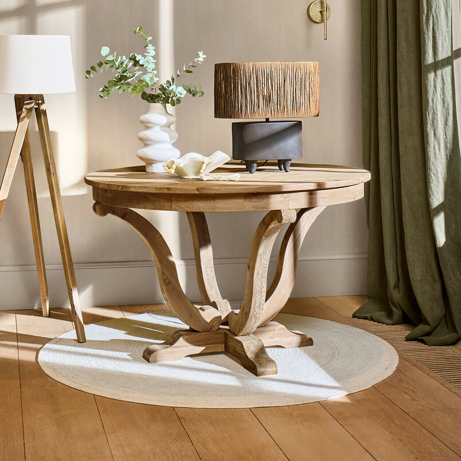 Tisch Oakminster Runder Couchtisch aus hellem Holz auf hellem Teppich mit Lampe und Vase im Wohnzimmer