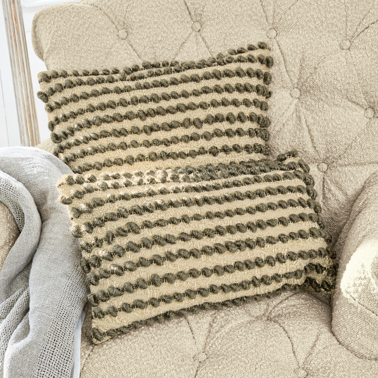 Kissenhülle 2er Set Madien Beige Dekokissen mit grünen Pompons auf beigem Polstersessel, Wohntextilien