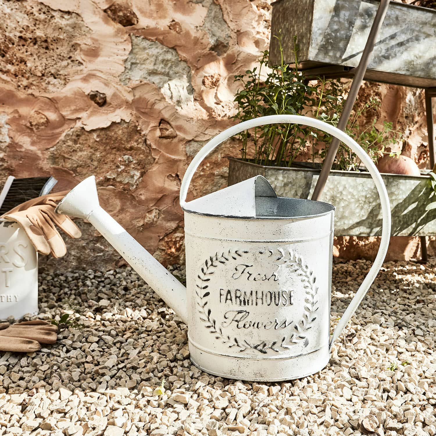 Gießkanne Farmhouse Weiße Metall-Gießkanne mit Farmhouse-Schriftzug auf Kiesboden zum Gießen von Pflanzen im Garten