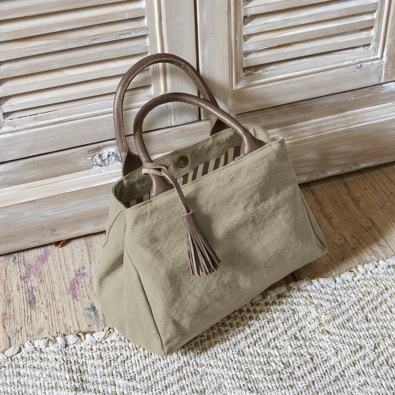 Tasche Hoya Beige Stofftasche mit braunen Ledergriffen und Quaste auf Holzboden