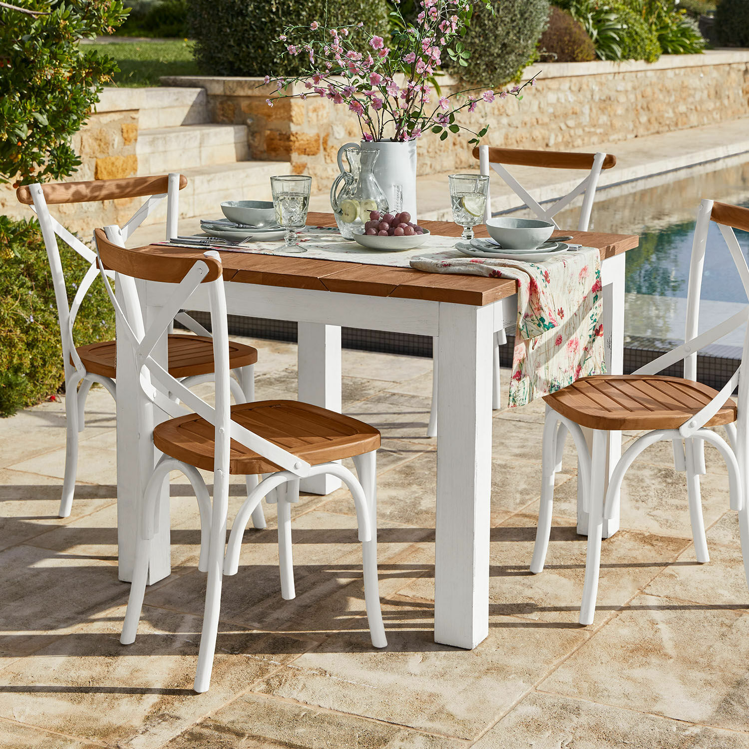 Tisch Kirkdale Gartenmöbel-Set mit weißem Holztisch und Stühlen mit Holzsitzflächen auf Steinterrasse